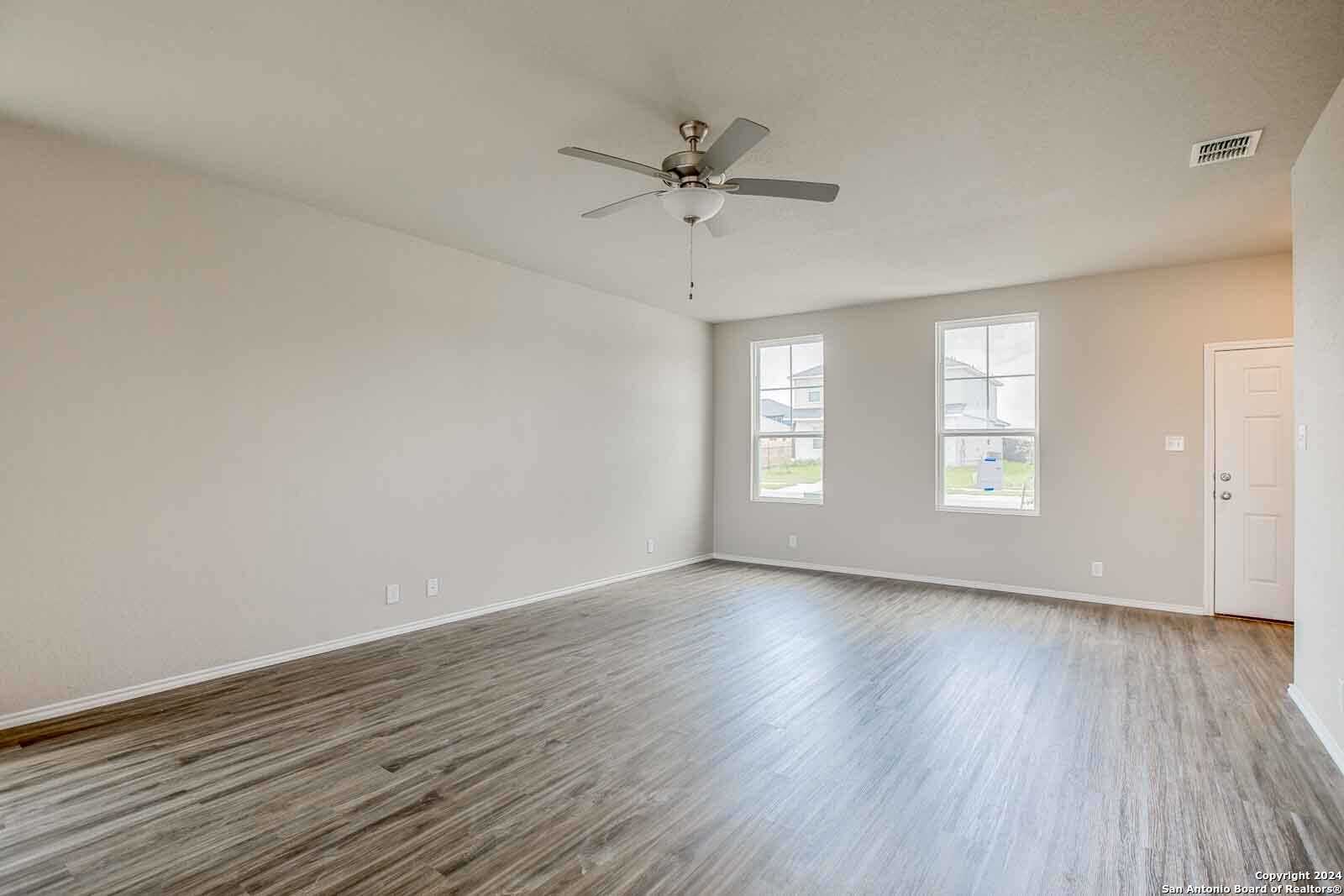 Spacious living room with ceiling fan, large windows, and hardwood floors in 4-bedroom Davidson Homes The Murray H, Seguin, Texas