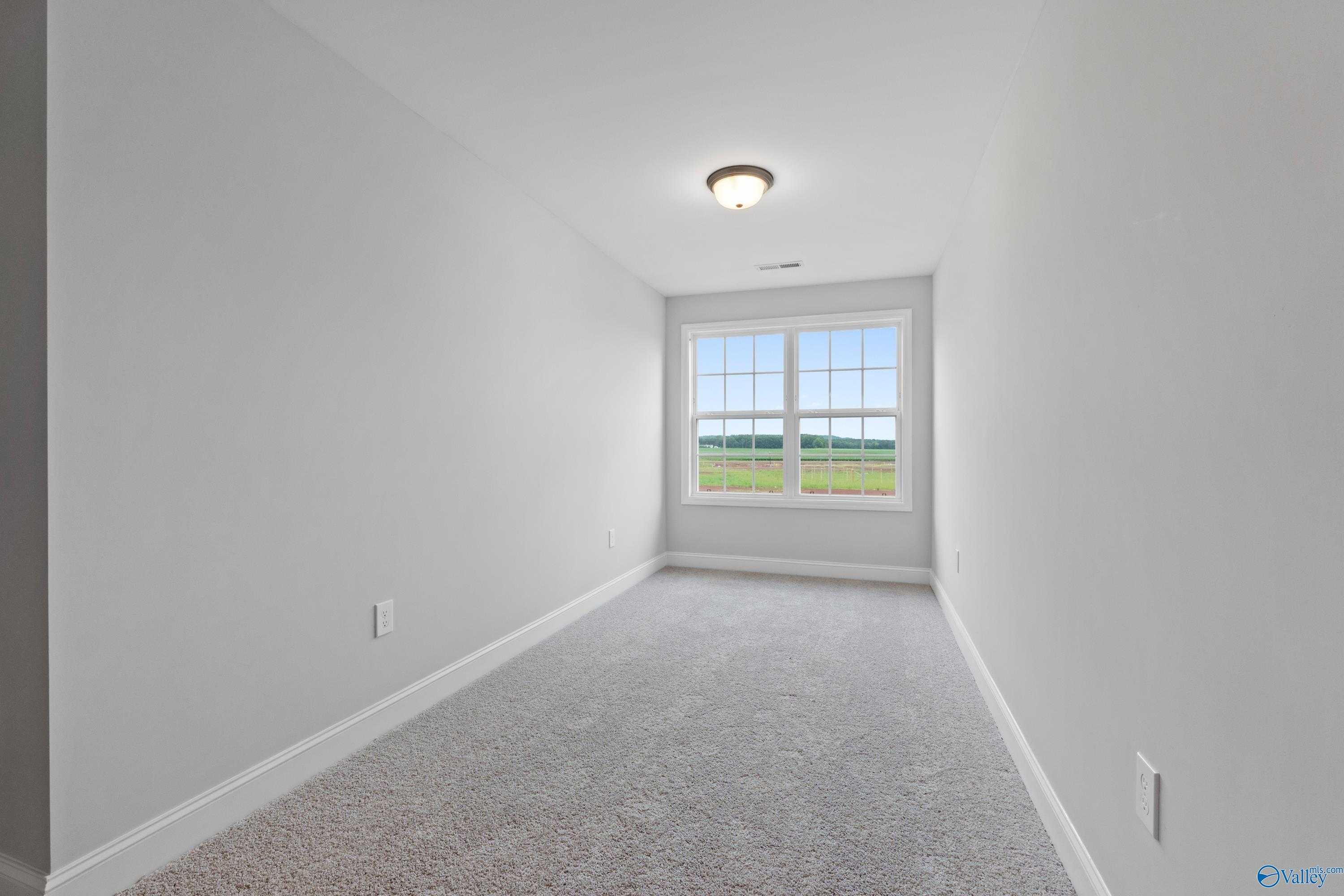 Bright secondary bedroom with large window overlooking green fields in Davidson Homes The Rockford B, Toney, Alabama