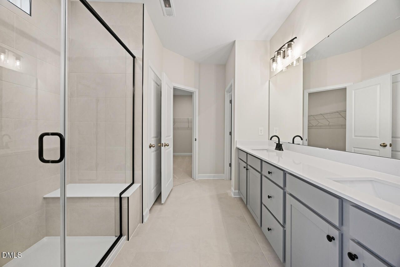 Modern bathroom with glass walk-in shower and double vanity in The Chestnut floor plan by Davidson Homes in Aberdeen, NC.