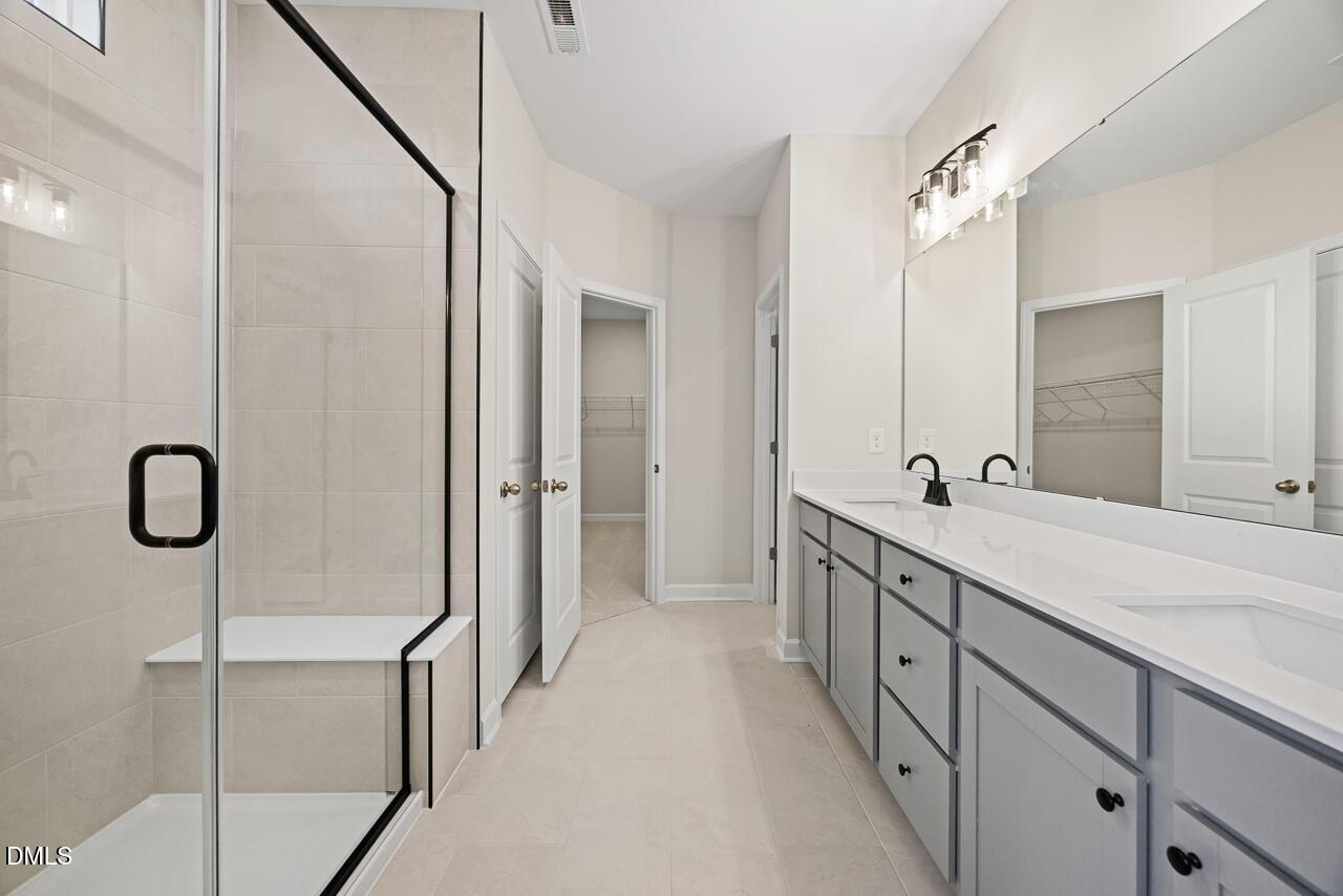 Modern bathroom with glass walk-in shower and double vanity in The Chestnut floor plan by Davidson Homes in Aberdeen, NC.