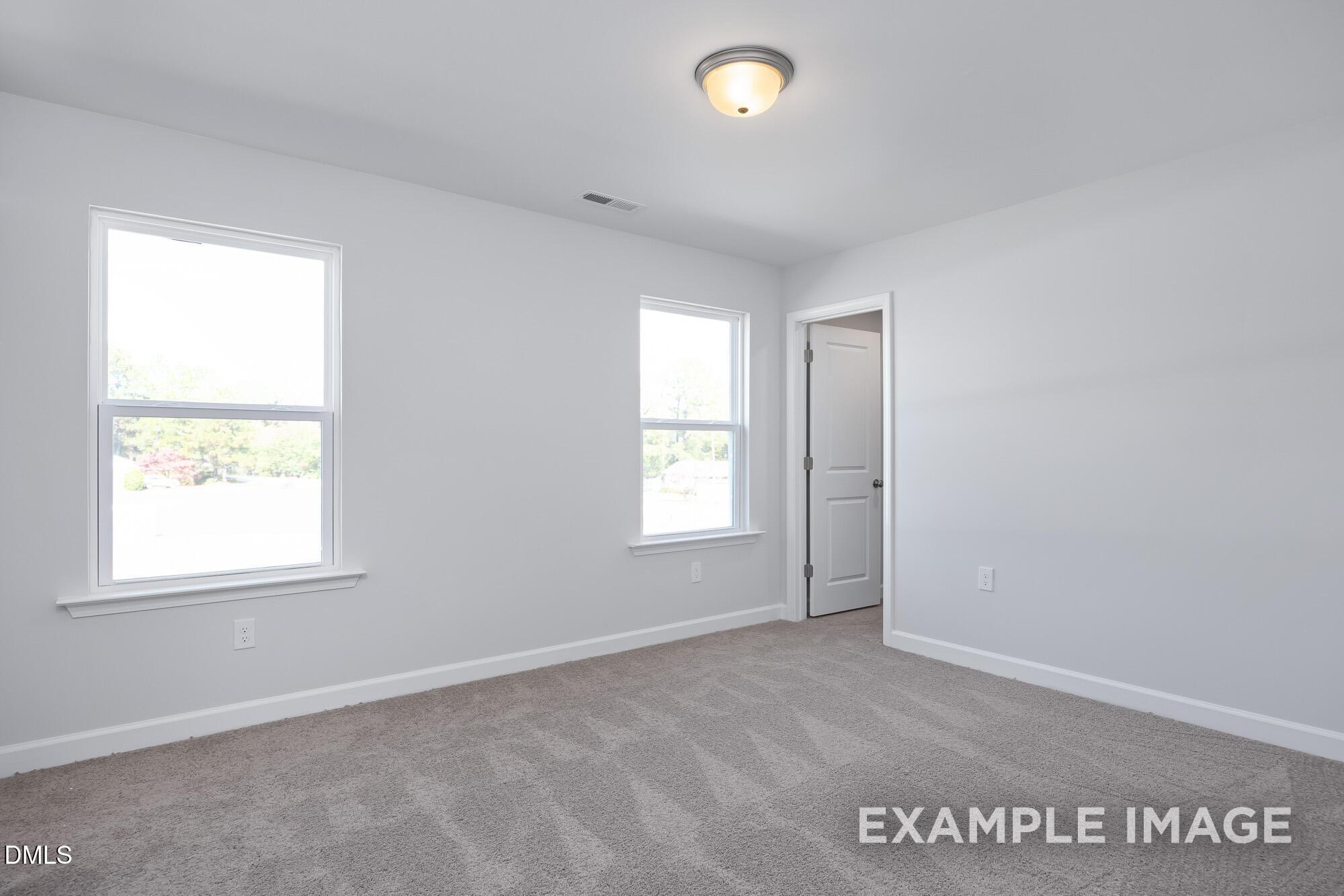 Bright bedroom with large windows, gray carpet, white walls in Davidson Homes The Hickory II B, Lillington, NC