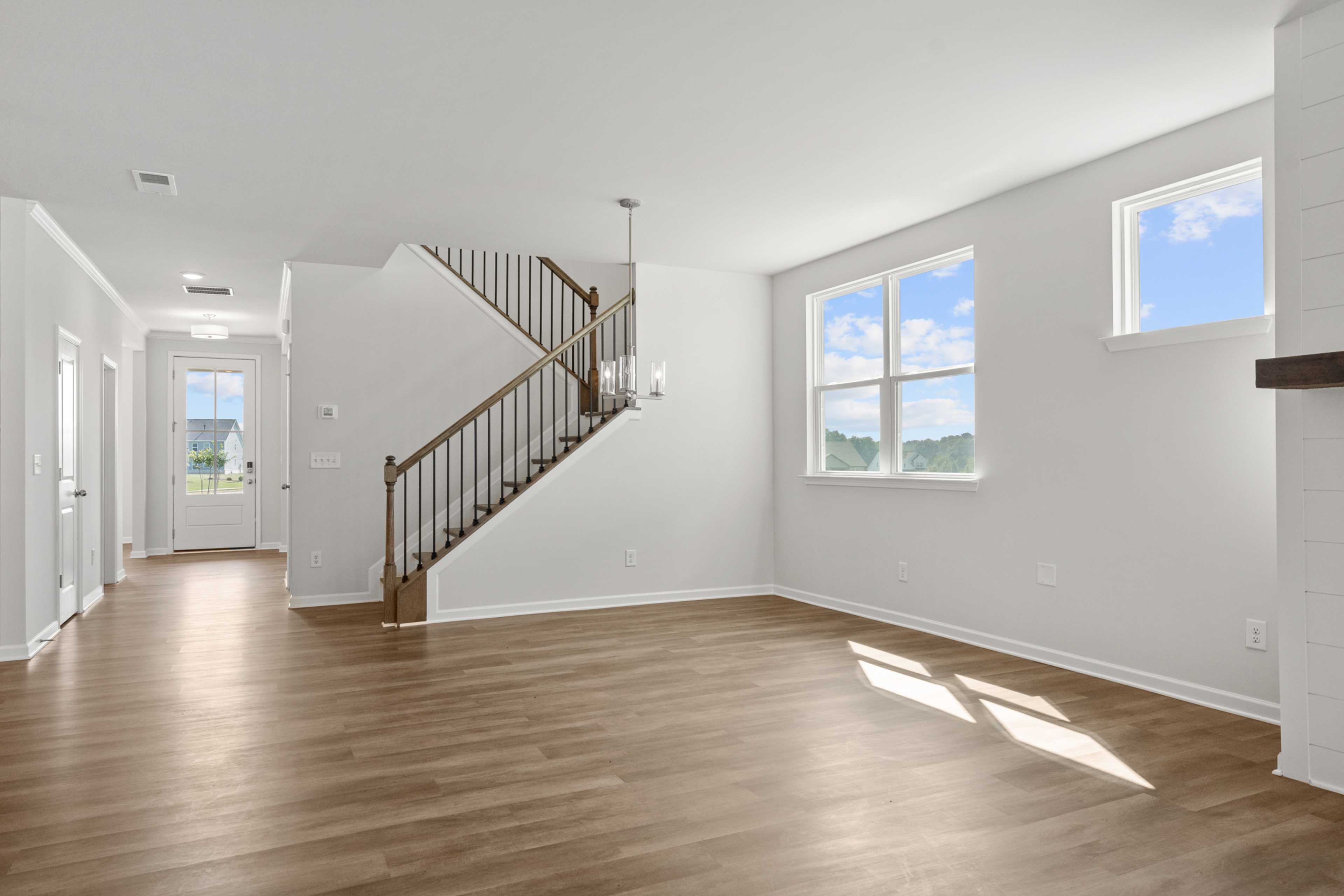 Spacious open foyer in Everleigh community, Locust Grove GA with wooden staircase, hardwood floors, large windows and chandelier