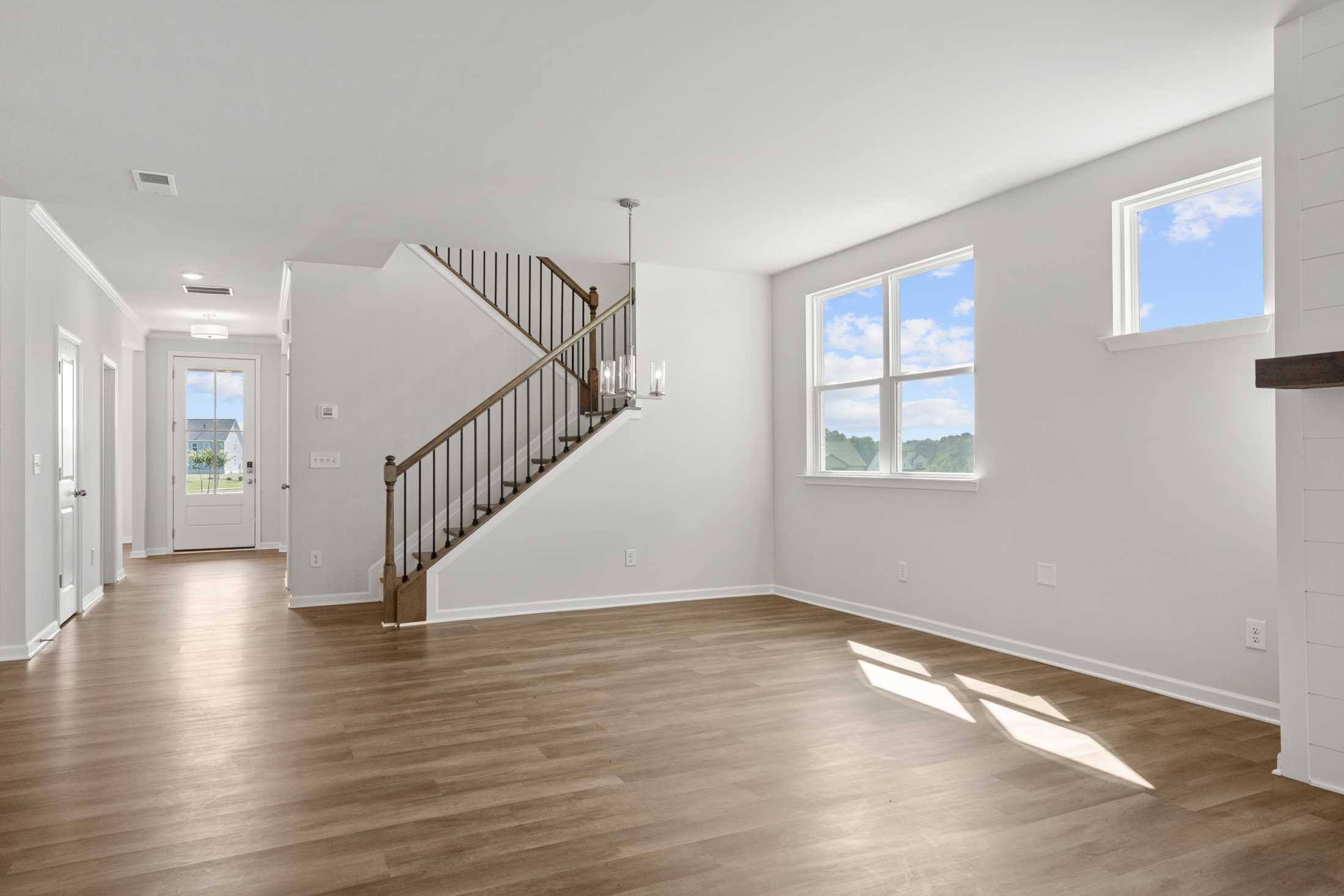 Spacious open foyer in Everleigh community, Locust Grove GA with wooden staircase, hardwood floors, large windows and chandelier