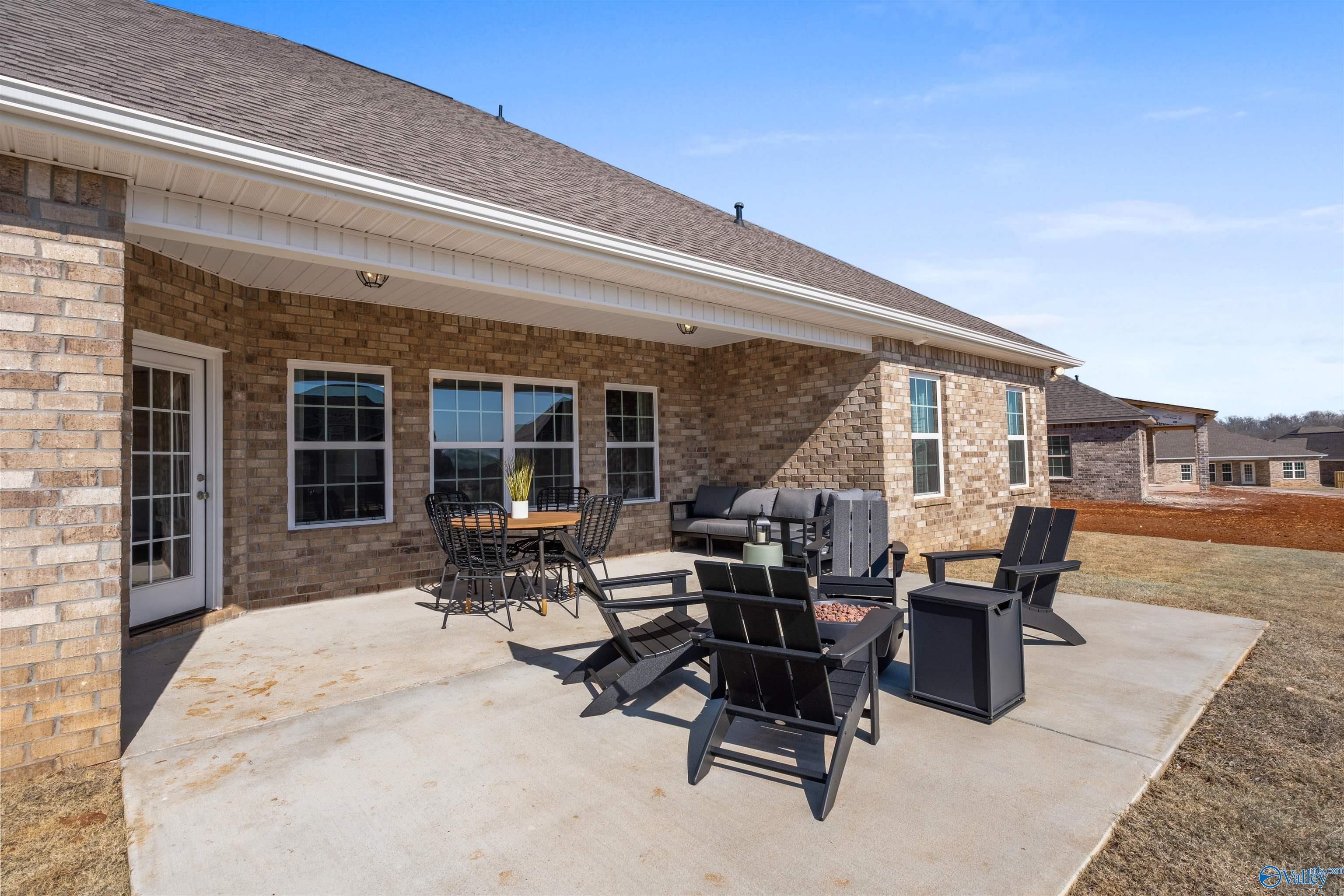 Covered back patio with Adirondack chairs, fire pit, and lounge seating on brick Davidson Homes The Rockford B in Barnett's Crossing, Madison, Alabama