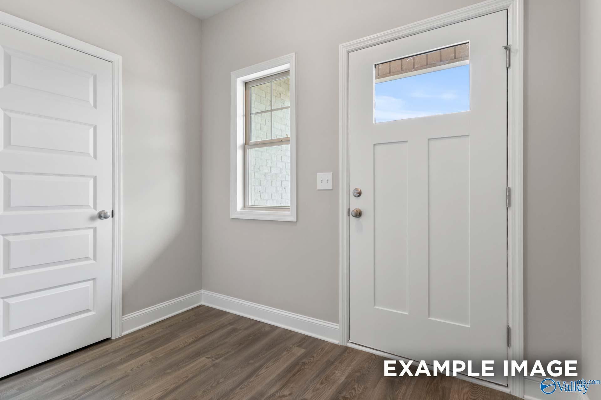 Bright entryway with glass-paneled front door, sidelight window, and hardwood floors in Davidson Homes The Camilla C, Hartselle, AL