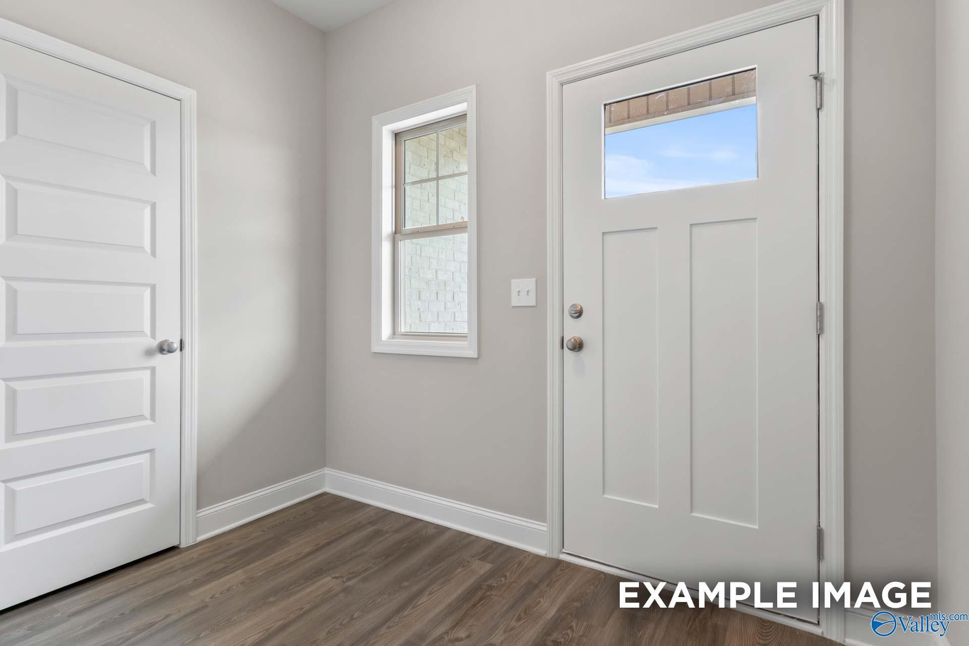 Bright entryway with glass-paneled front door, sidelight window, and hardwood floors in Davidson Homes The Camilla C, Hartselle, AL