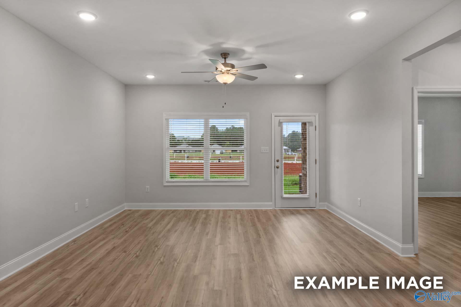 Bright living room with ceiling fan, large windows, sliding glass door, and hardwood floors in Davidson Homes The Cumberland B, Decatur, Alabama