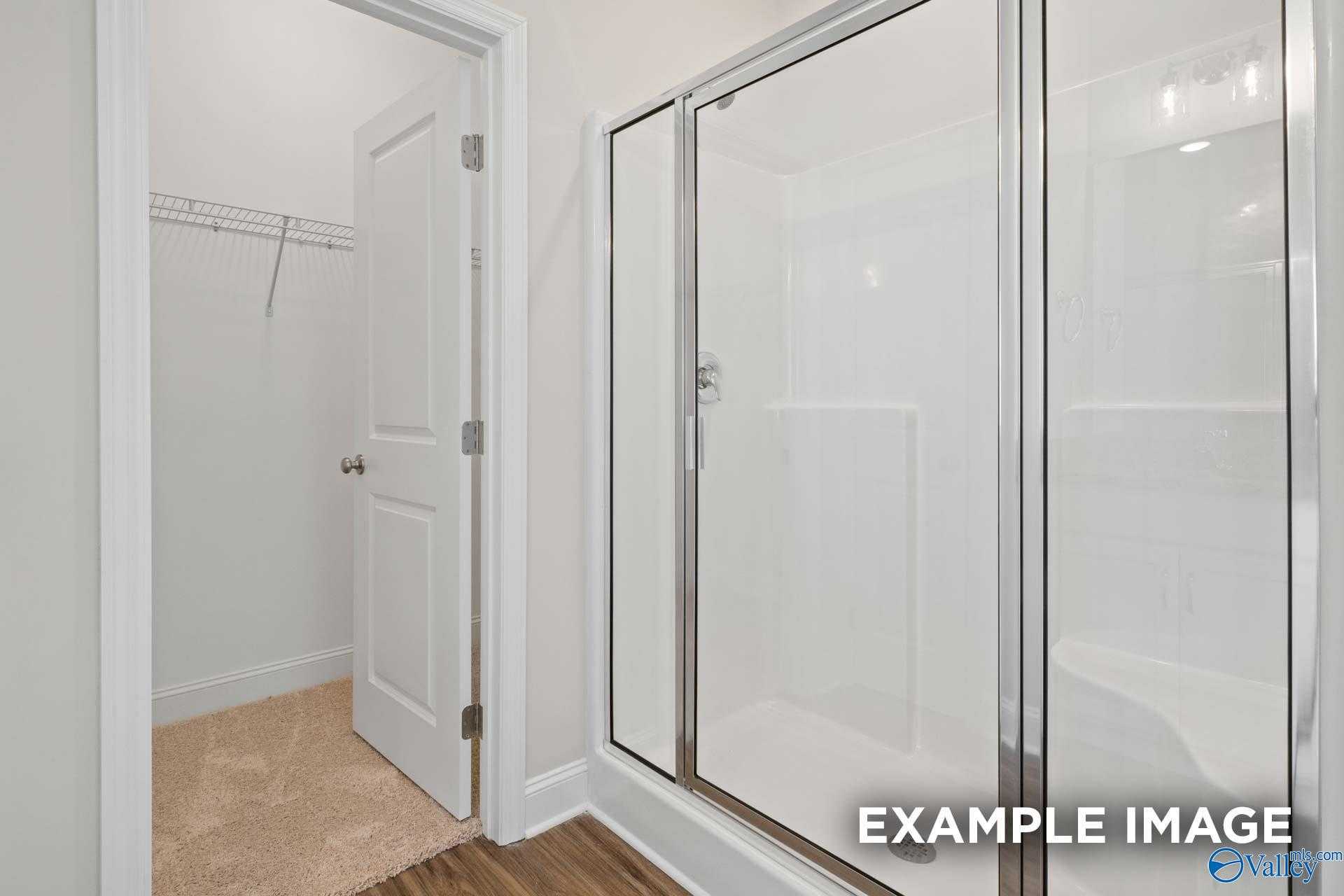 Modern master bathroom with frameless glass shower and walk-in closet in Davidson Homes The Franklin, Meridianville, Alabama