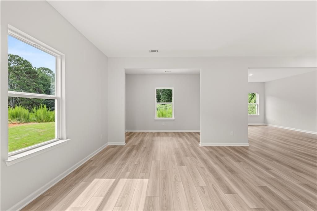 Bright, open-concept living area with wood-style flooring in The Russell A floor plan at Cedar Farms in Winder, Georgia.