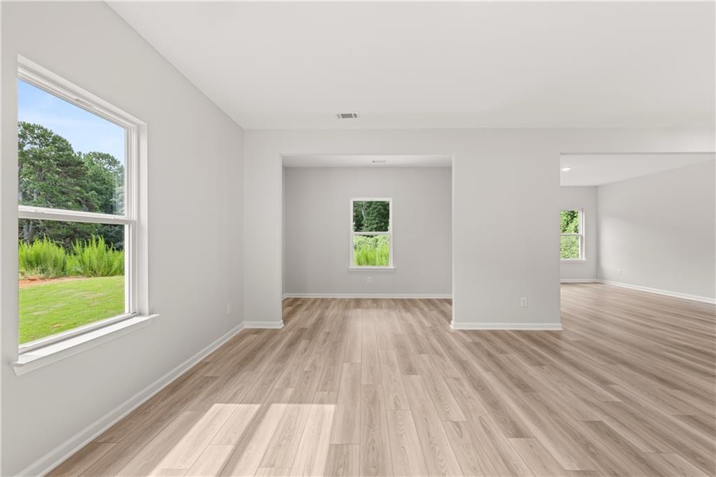Bright, open-concept living area with wood-style flooring in The Russell A floor plan at Cedar Farms in Winder, Georgia.