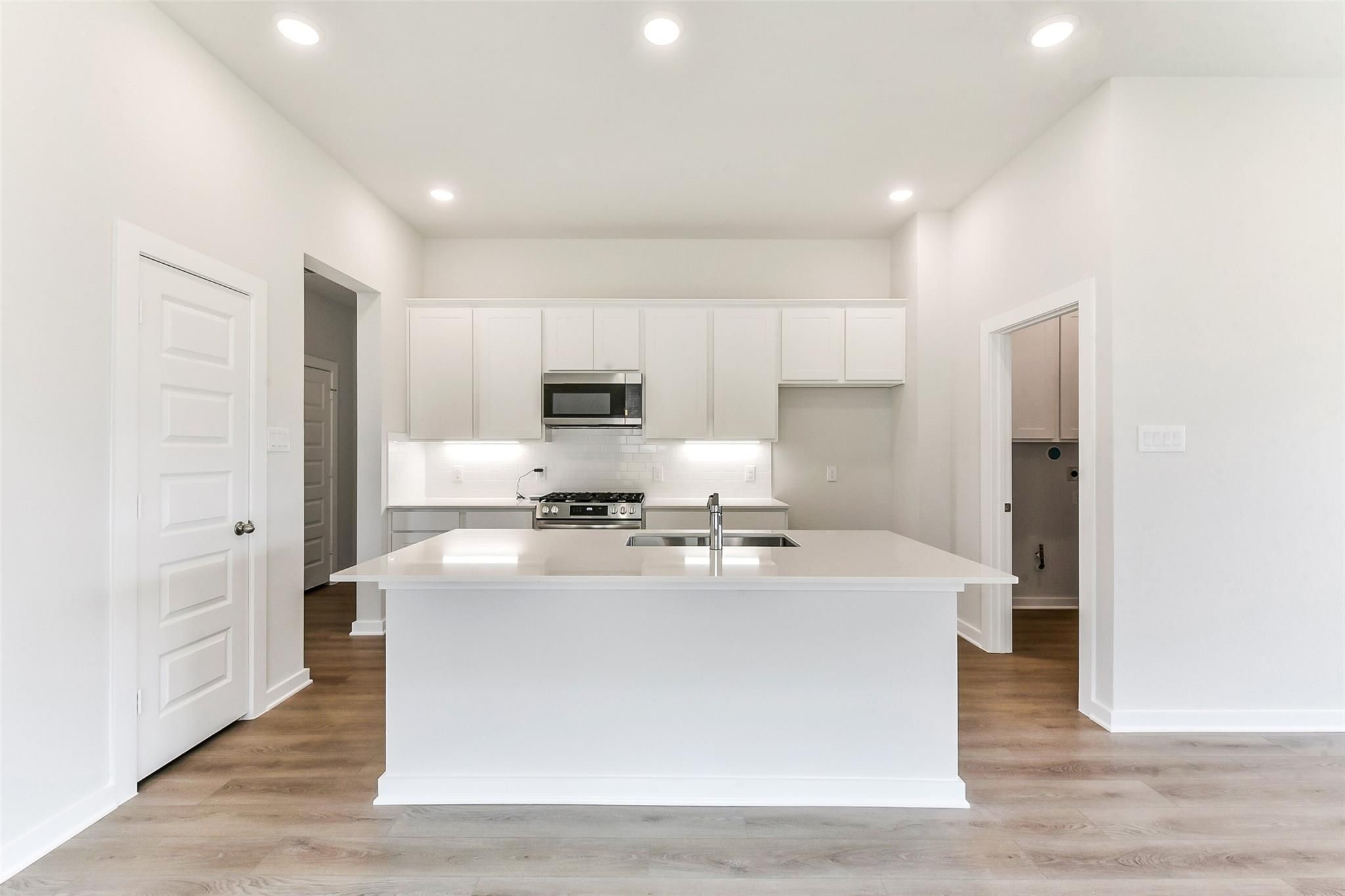 Bright modern kitchen with white shaker cabinets, quartz island sink, stainless appliances in Davidson Homes The Costa B, Dayton Texas