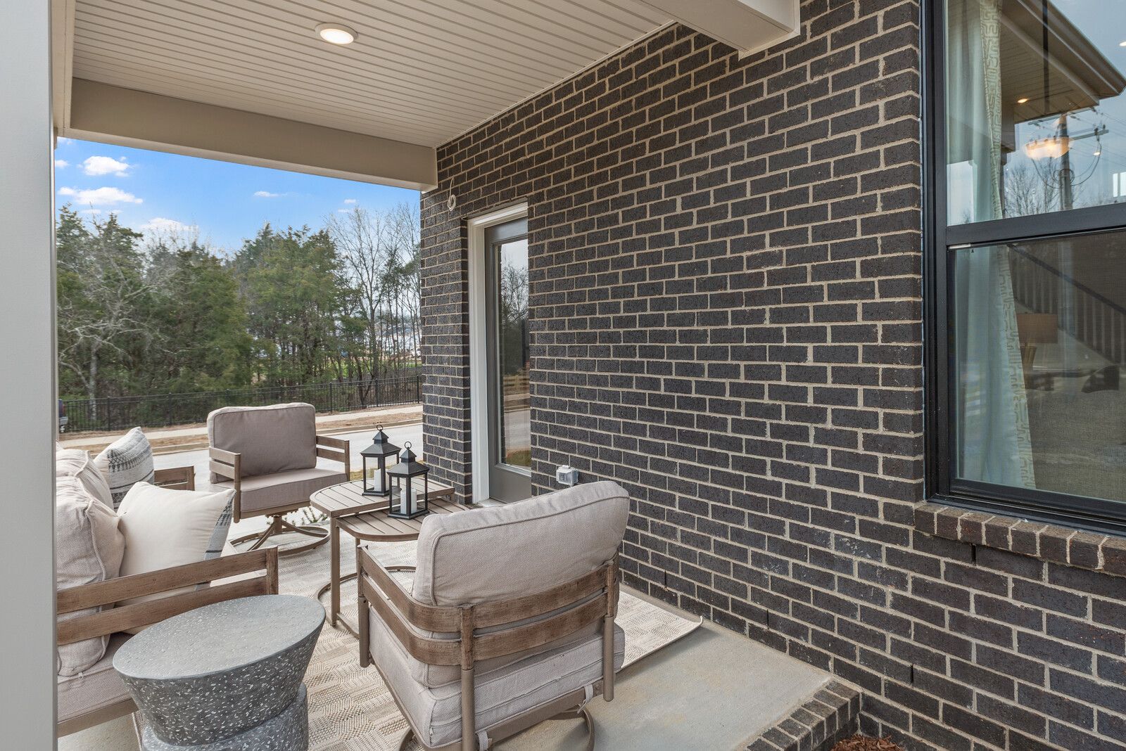 Covered outdoor patio at Benders Cove in Mt. Juliet, TN by Davidson Homes featuring lounge seating and brick exterior.