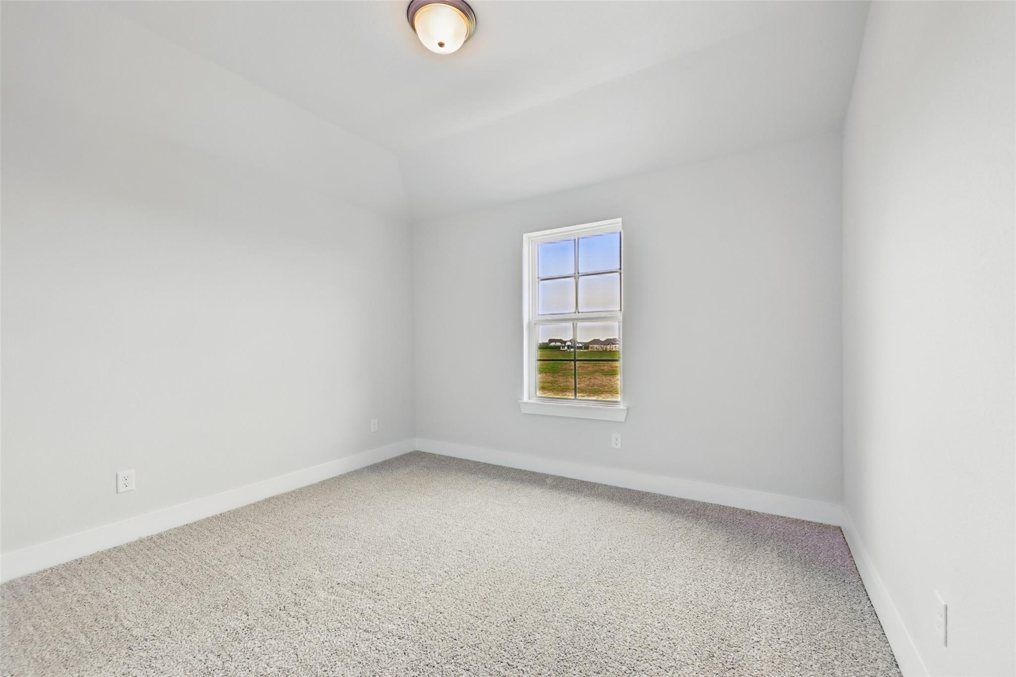 Bright secondary bedroom with beige carpet, white walls, and large window overlooking fields in Davidson Homes The Philip A, Lago Mar, Texas City