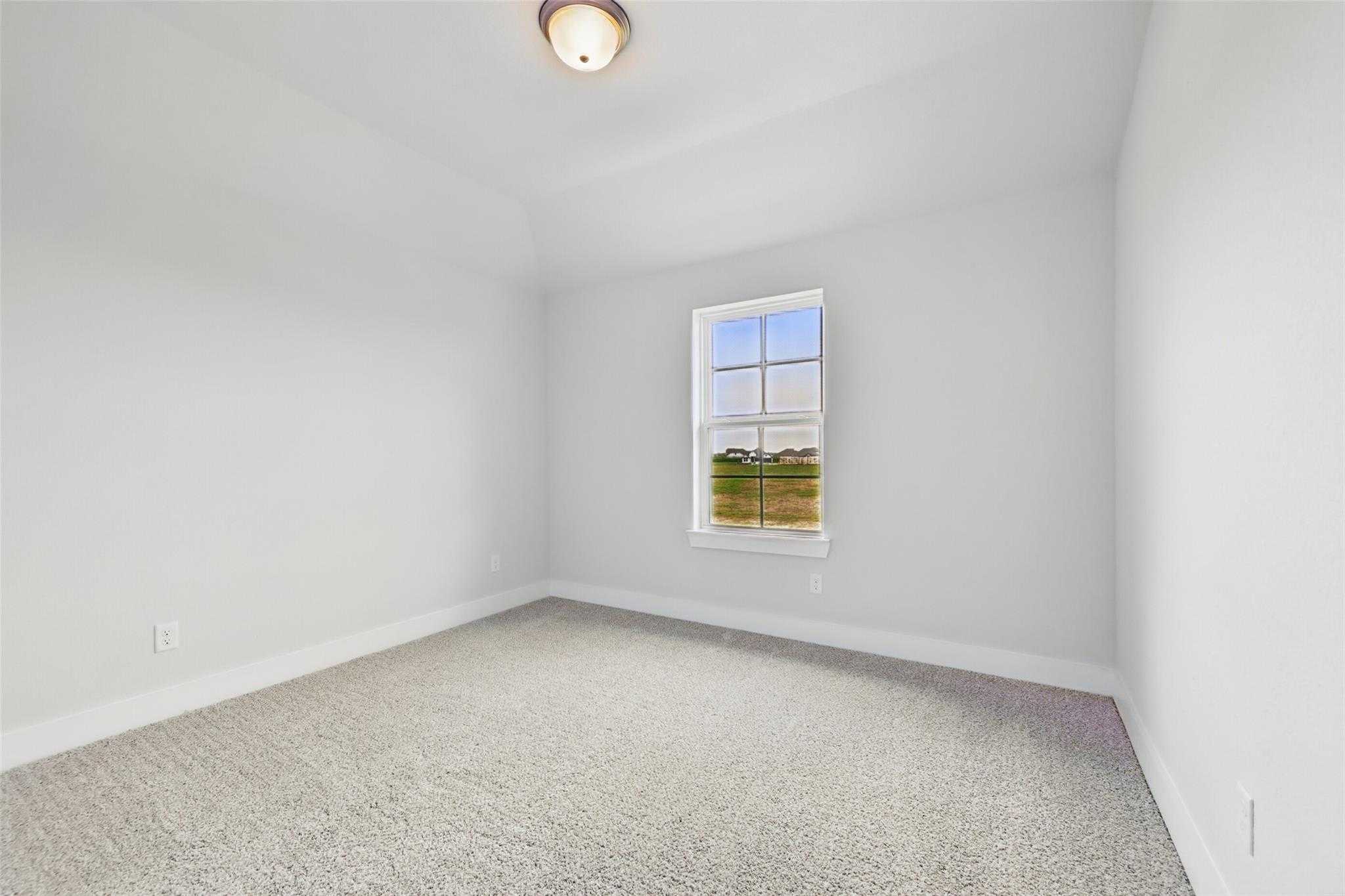 Bright secondary bedroom with beige carpet, white walls, and large window overlooking fields in Davidson Homes The Philip A, Lago Mar, Texas City