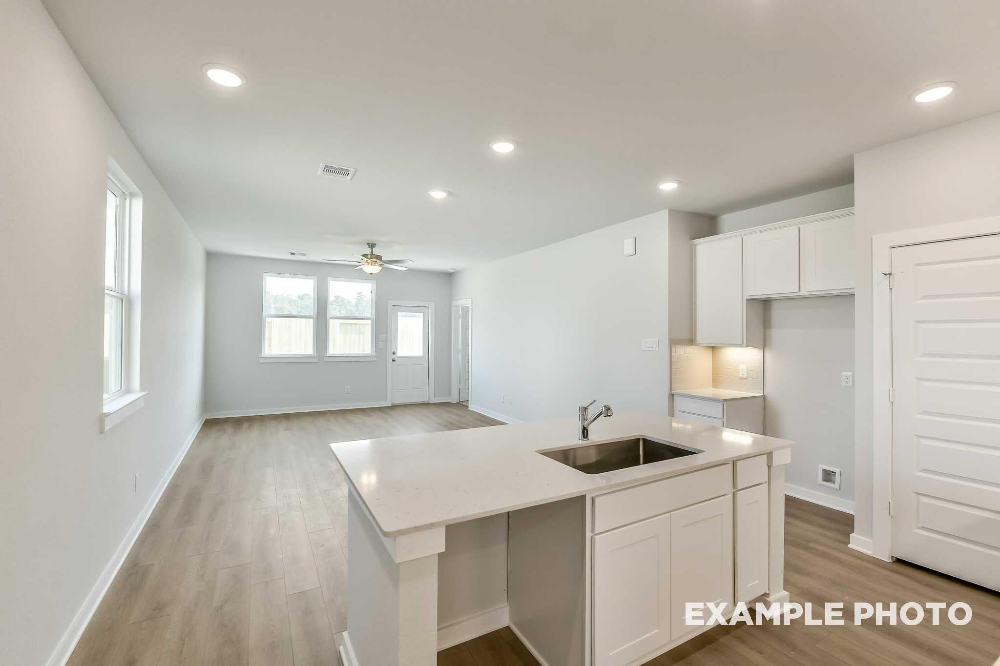 Open-concept kitchen with white shaker cabinets, quartz island sink, and recessed lighting in Davidson Homes The Colorado G, Conroe, Texas