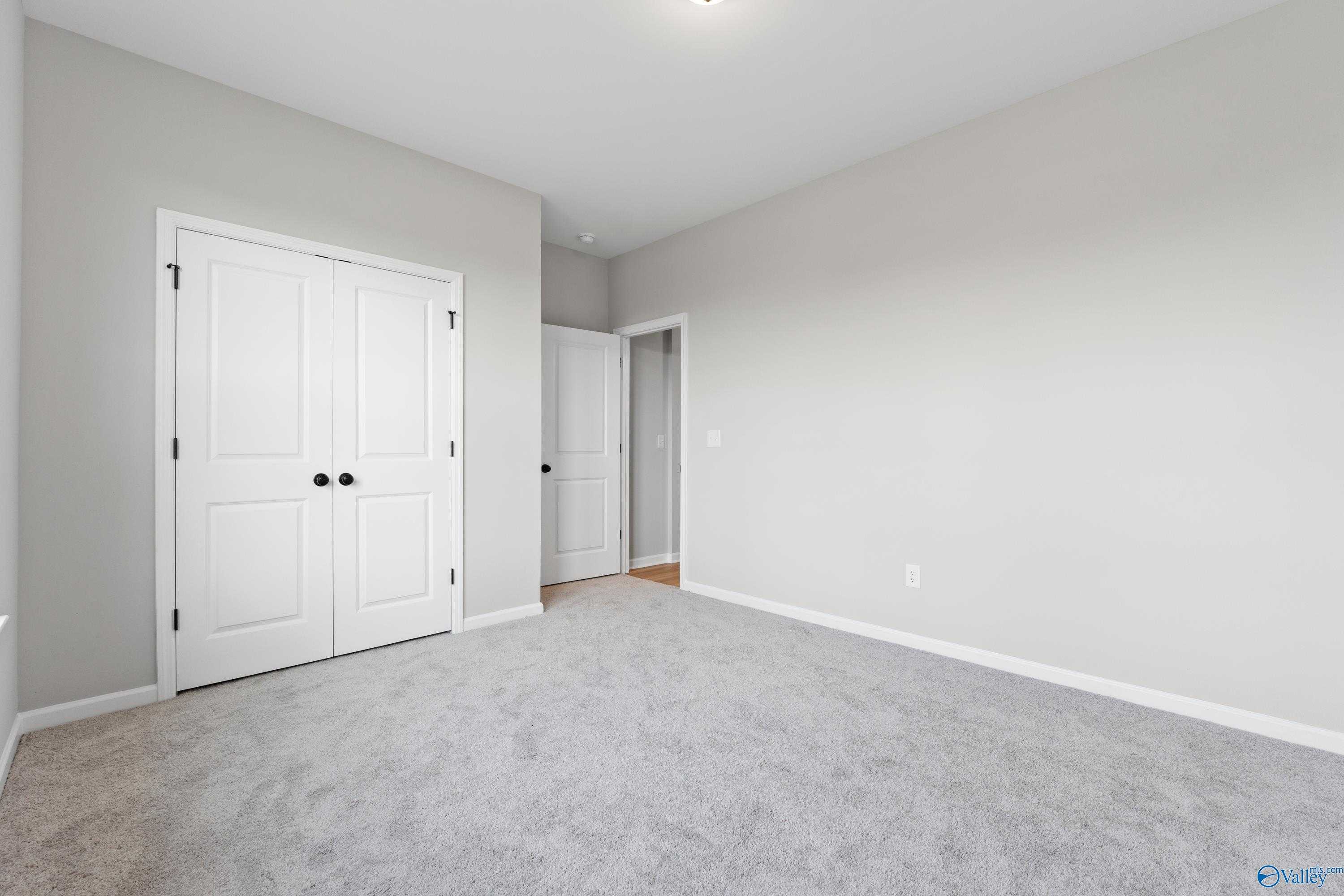 Light gray secondary bedroom with double closet doors and bathroom access in Davidson Homes The Phoenix, Fayetteville, TN