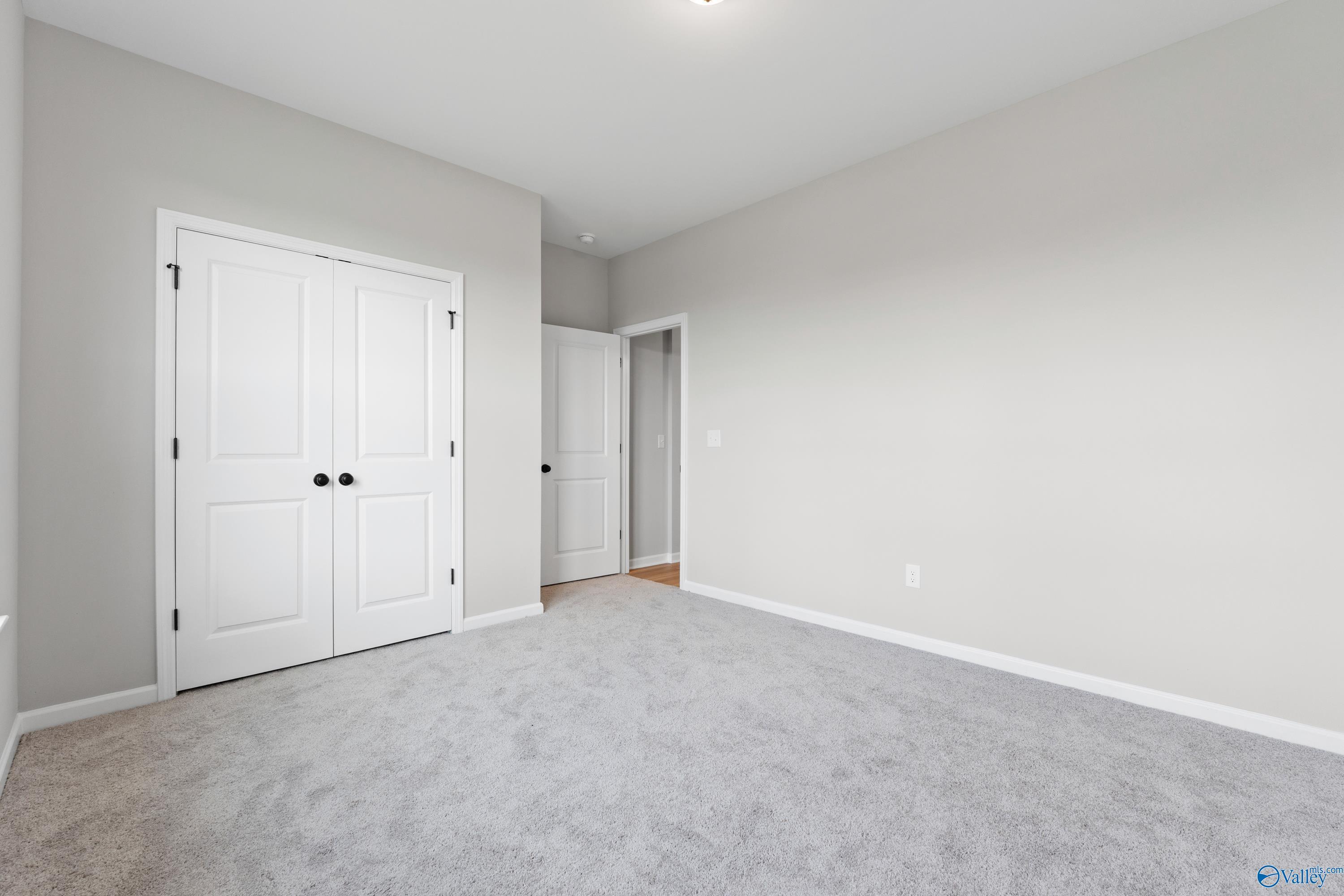 Spacious secondary bedroom with gray walls, plush carpet, double closet doors in Davidson Homes The Phoenix, Fayetteville, TN
