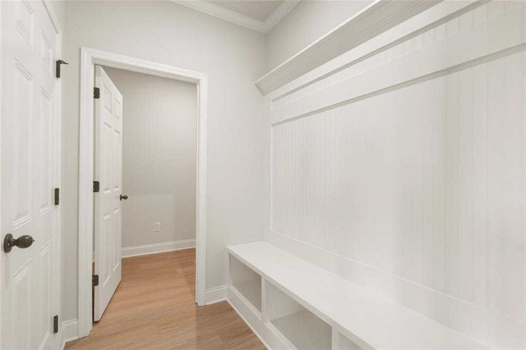 Bright mudroom with white shiplap walls, built-in bench, and open shelves in Davidson Homes The Ash B at Wehunt Meadows, Hoschton, GA