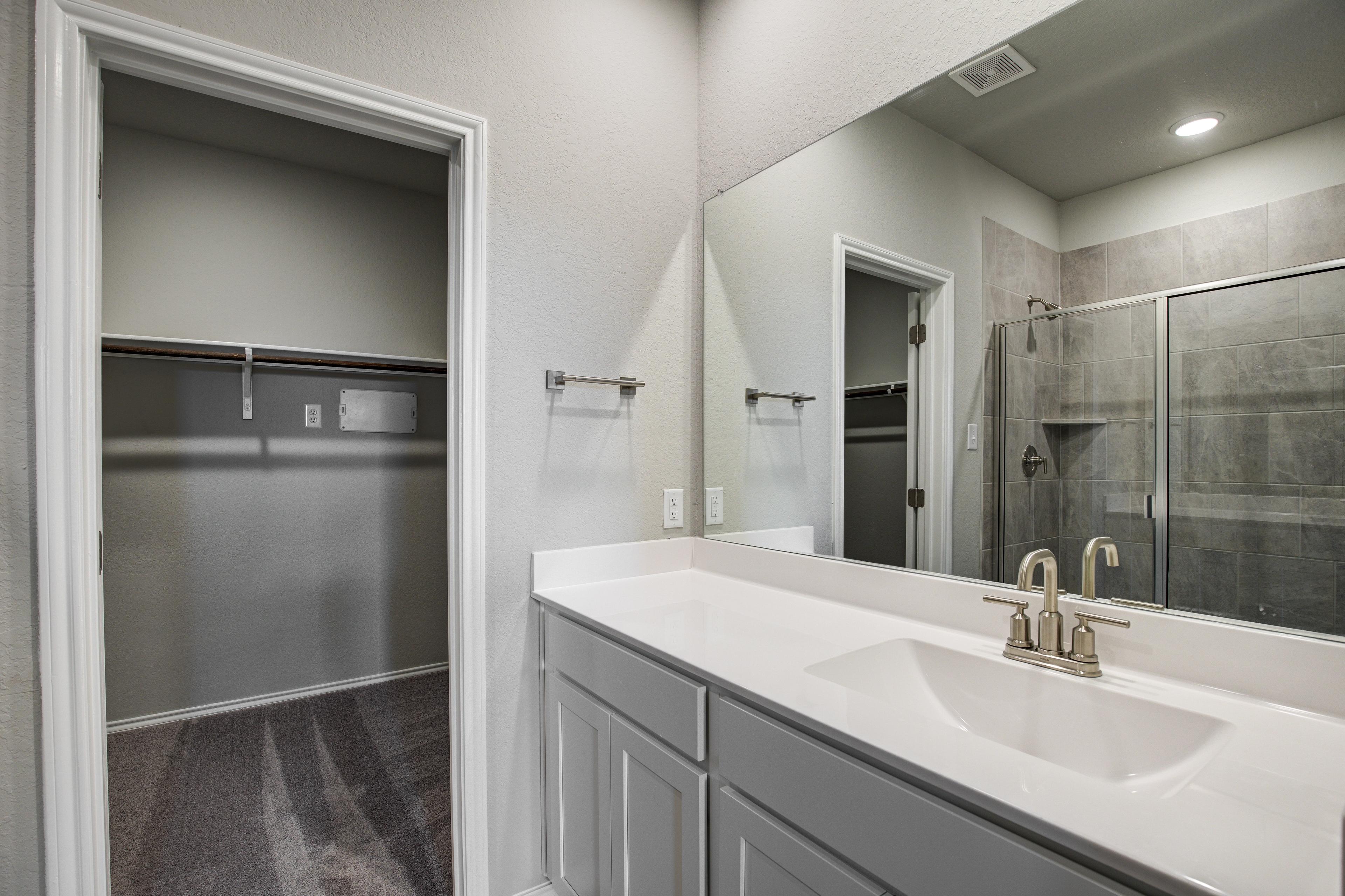 Modern master bathroom in The Blanco C by Davidson Homes featuring double vanity, walk-in shower, and closet