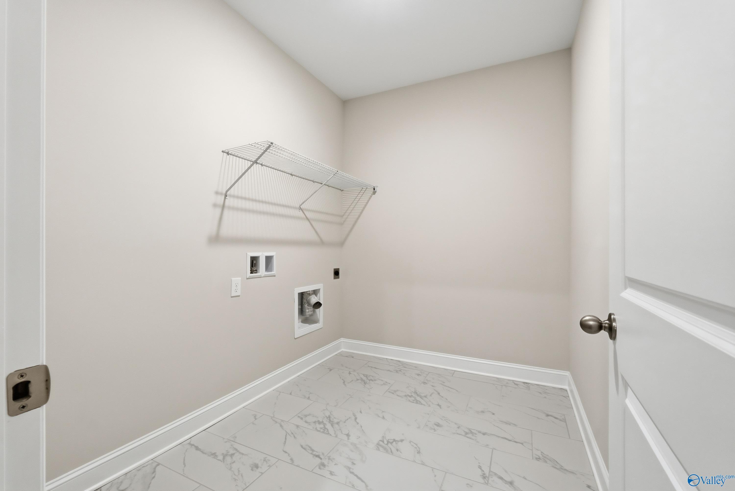 Spacious laundry room with wire shelving, washer dryer hookups, and marble-look tile floor in Davidson Homes The Finleigh, Creekside, Harvest, Alabama