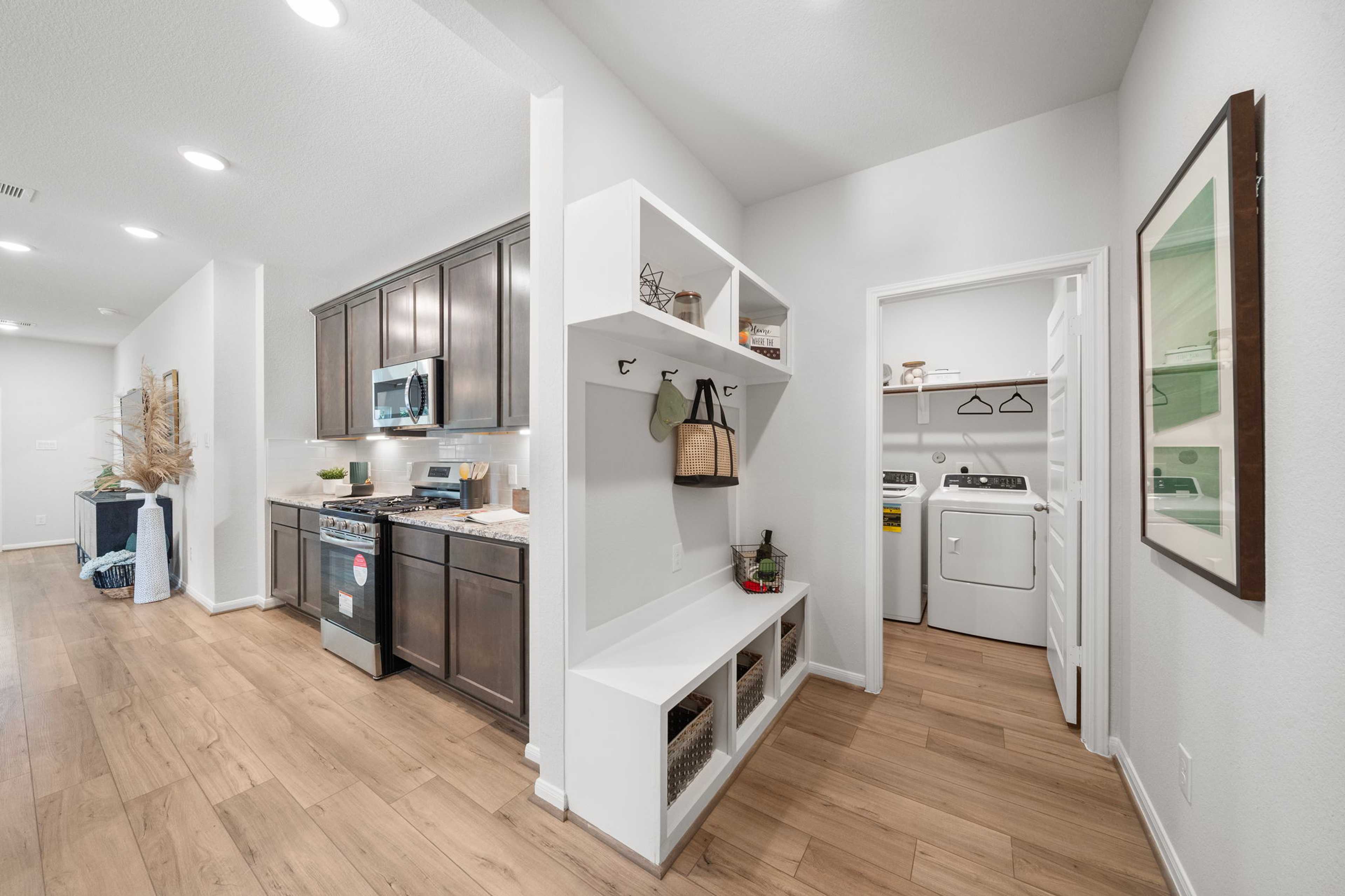 Modern kitchen and laundry area at Caney Creek Place in Conroe Texas with shaker cabinets, stainless appliances, hardwood floors, built-in bench