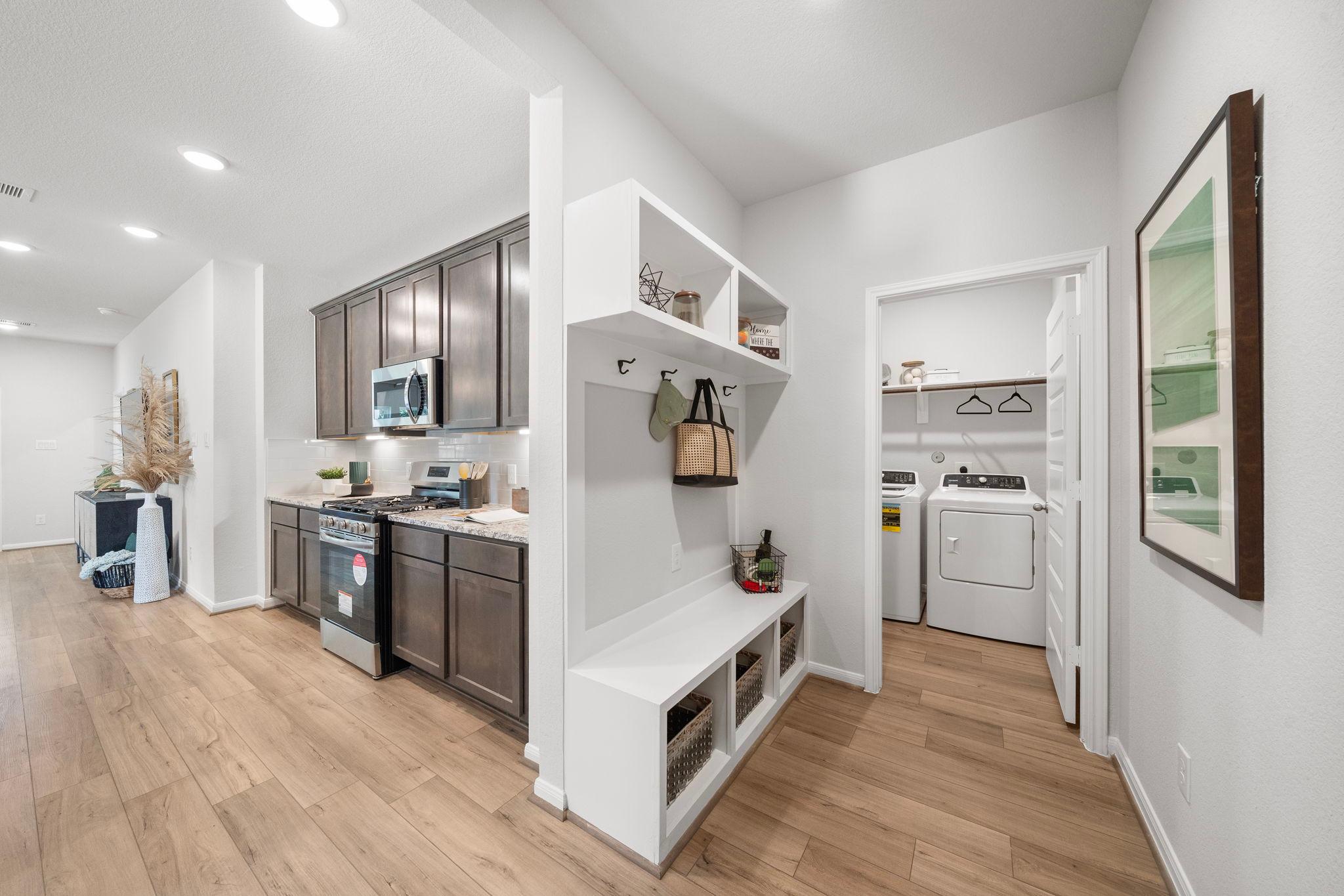 Modern kitchen and laundry area at Caney Creek Place in Conroe Texas with shaker cabinets, stainless appliances, hardwood floors, built-in bench