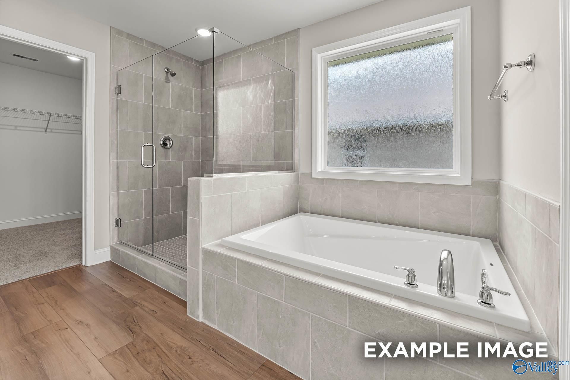 Elegant master bathroom featuring glass shower, corner soaking tub, gray tiles, and frosted window in Davidson Homes The Chelsea B, Toney, AL