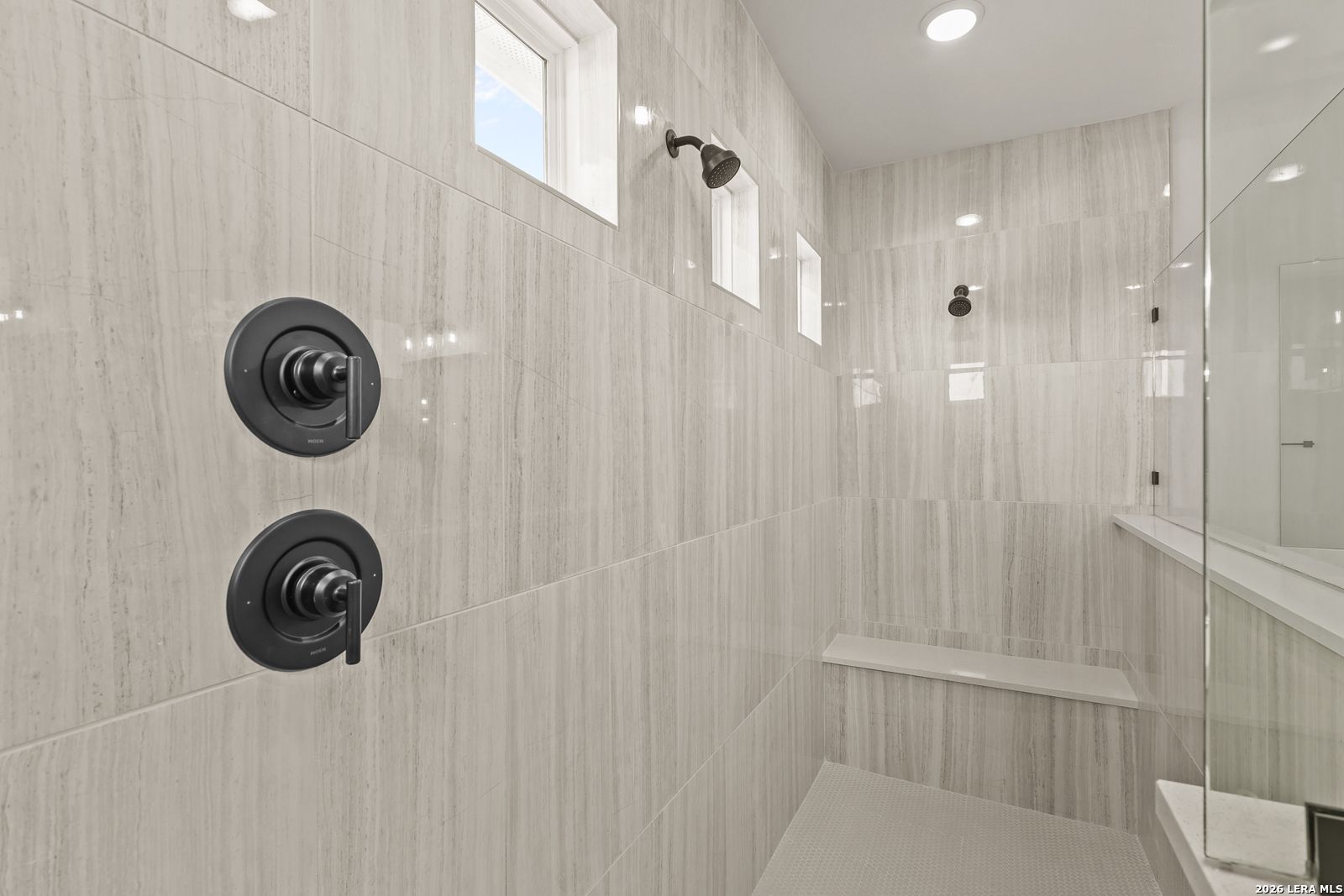Walk-in tiled shower with bench seat and matte black fixtures in The Summerlin B floor plan at Potranco Oaks, Castroville.