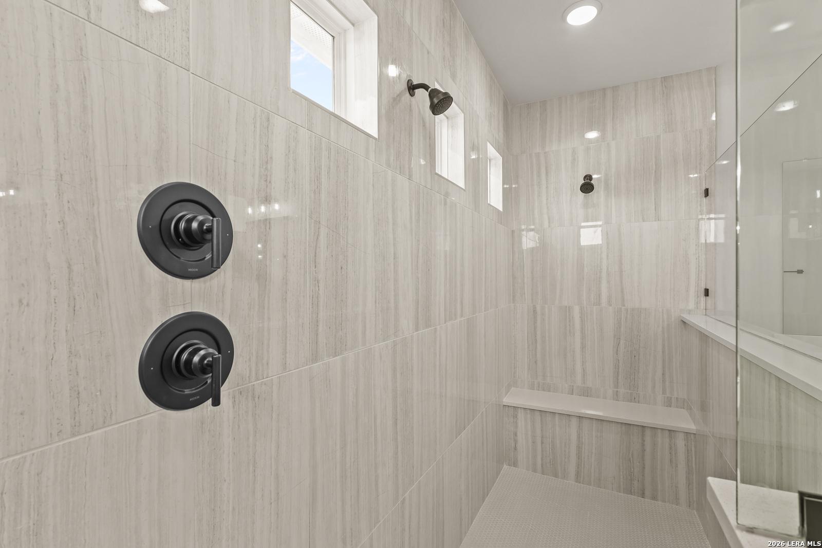 Walk-in tiled shower with bench seat and matte black fixtures in The Summerlin B floor plan at Potranco Oaks, Castroville.