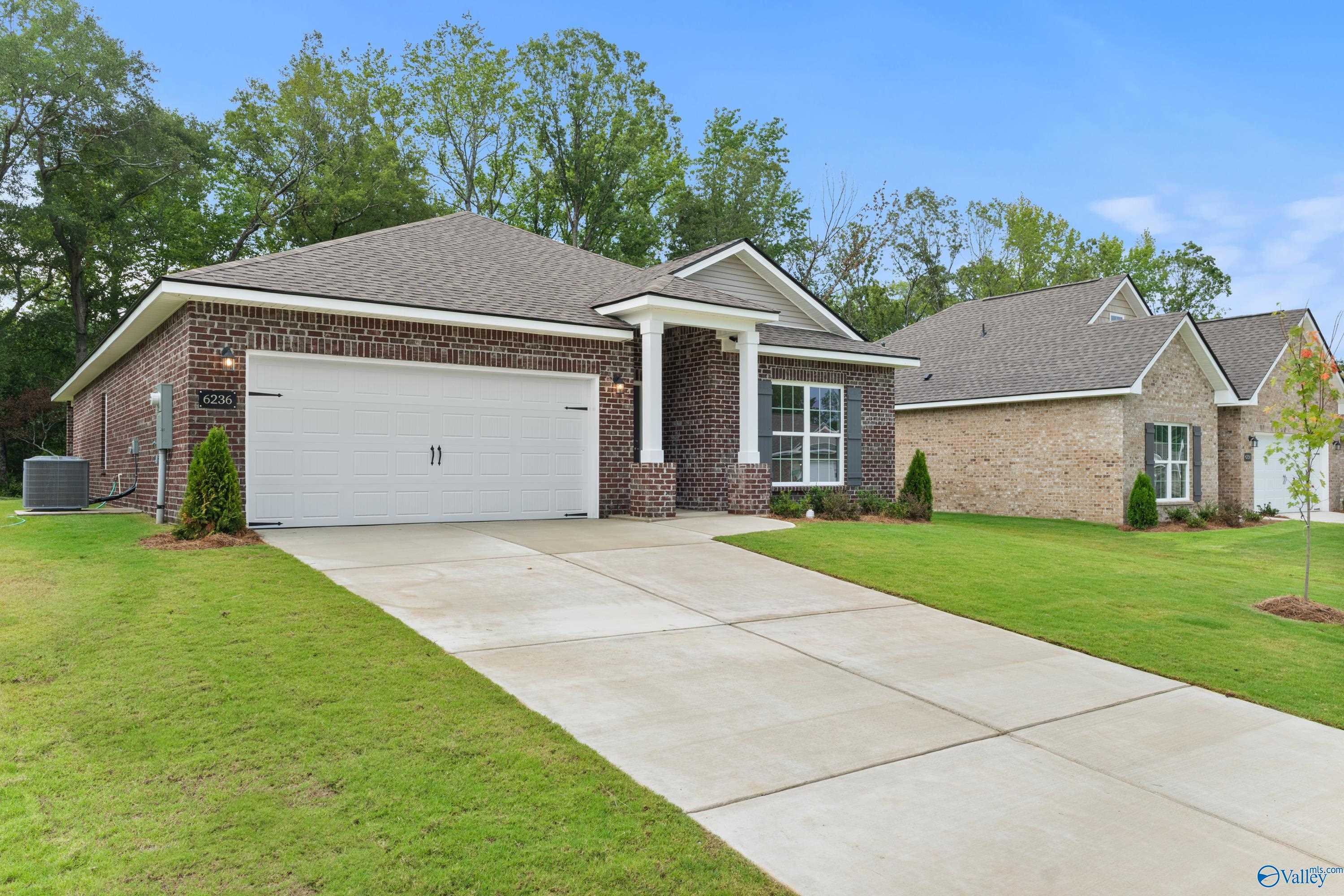 Brick ranch-style home with 2-car garage, covered porch, and lush green lawn in Spragins Cove, Huntsville, Alabama