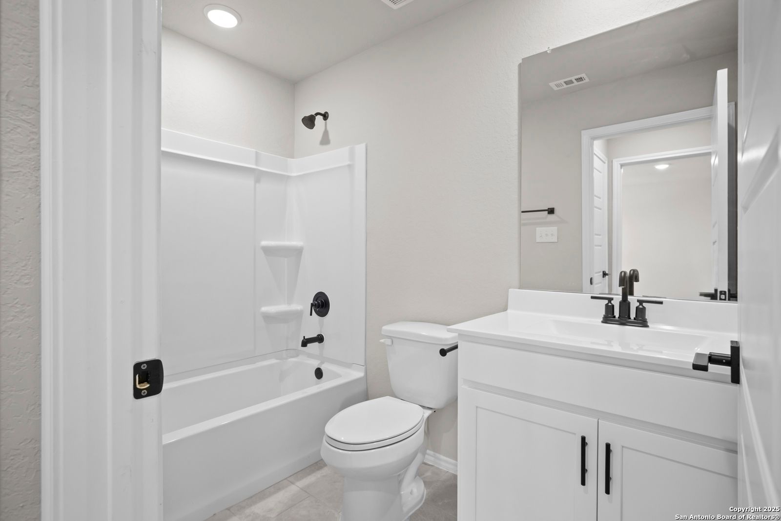 Modern secondary bathroom with white tub-shower combo, single vanity, and toilet in Davidson Homes The Sequoia A, Converse, Texas