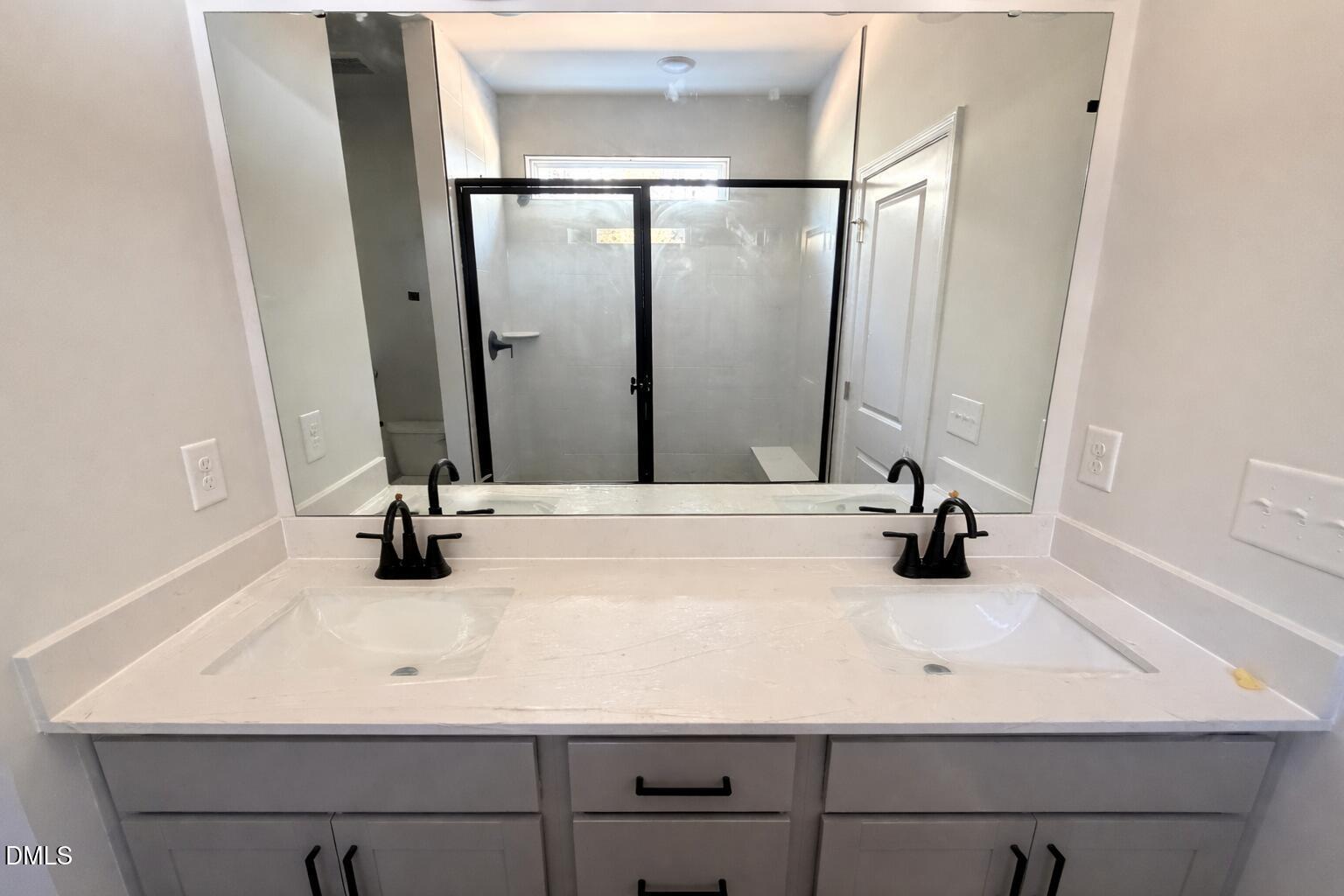 Modern master bathroom with double vanity sinks, glass walk-in shower, and large mirrors in Davidson Homes The Carter C, Lillington, NC