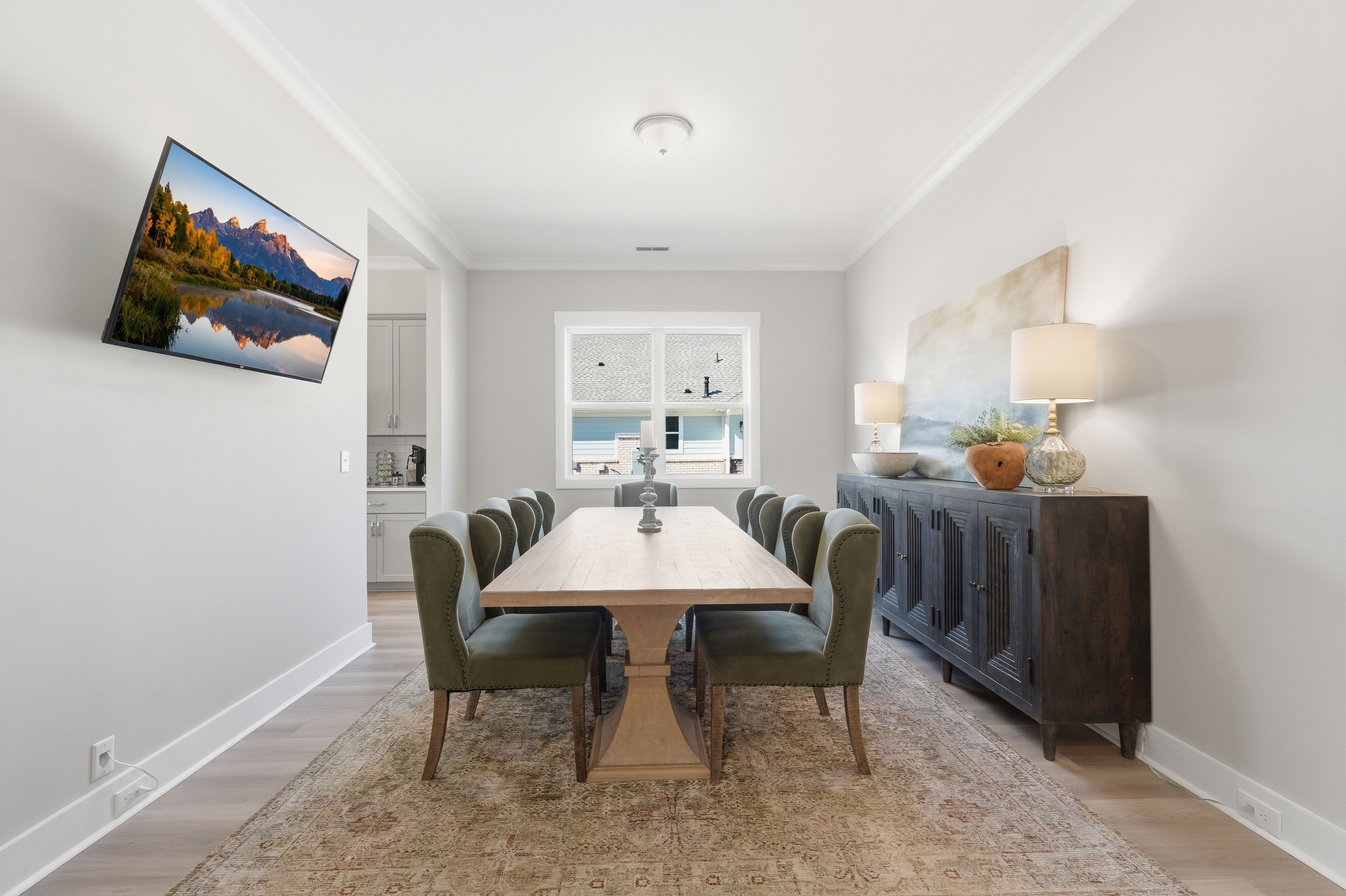 Elegant dining room at The Meadows at Hampton Cove in Owens Cross Roads AL with wooden table, green chairs, and scenic mountain TV