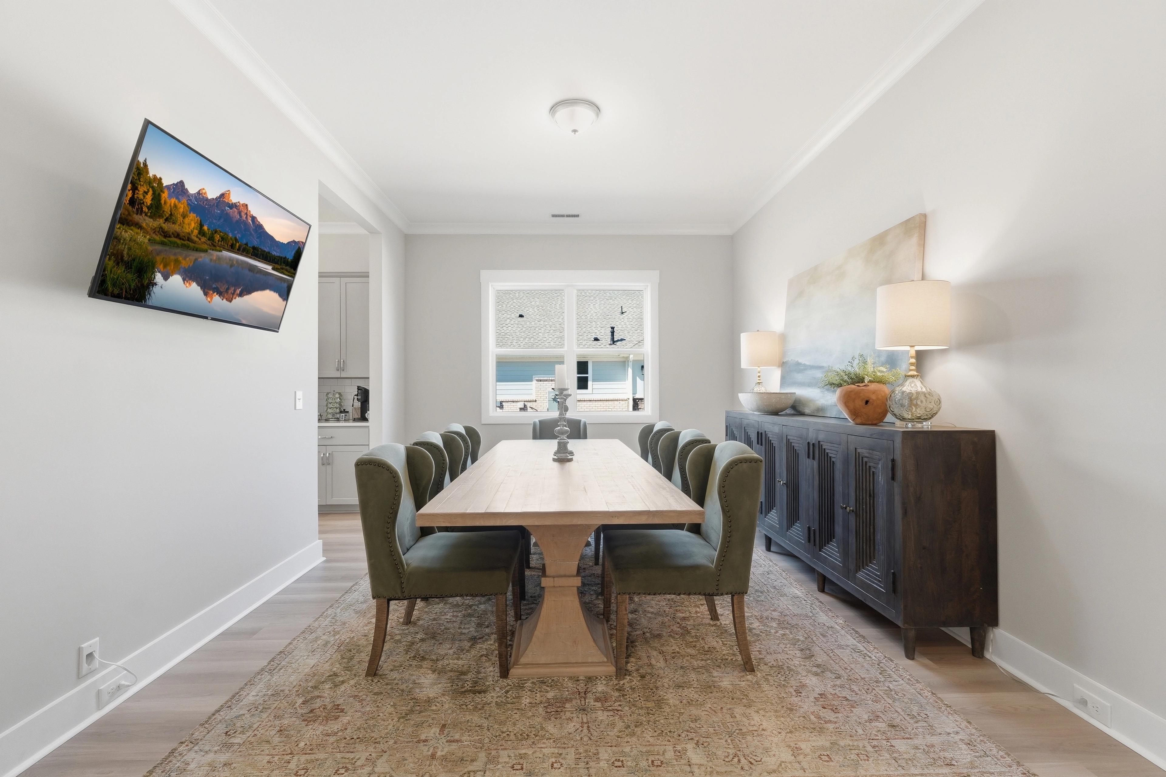 Elegant dining room at The Meadows at Hampton Cove in Owens Cross Roads AL with wooden table, green chairs, and scenic mountain TV