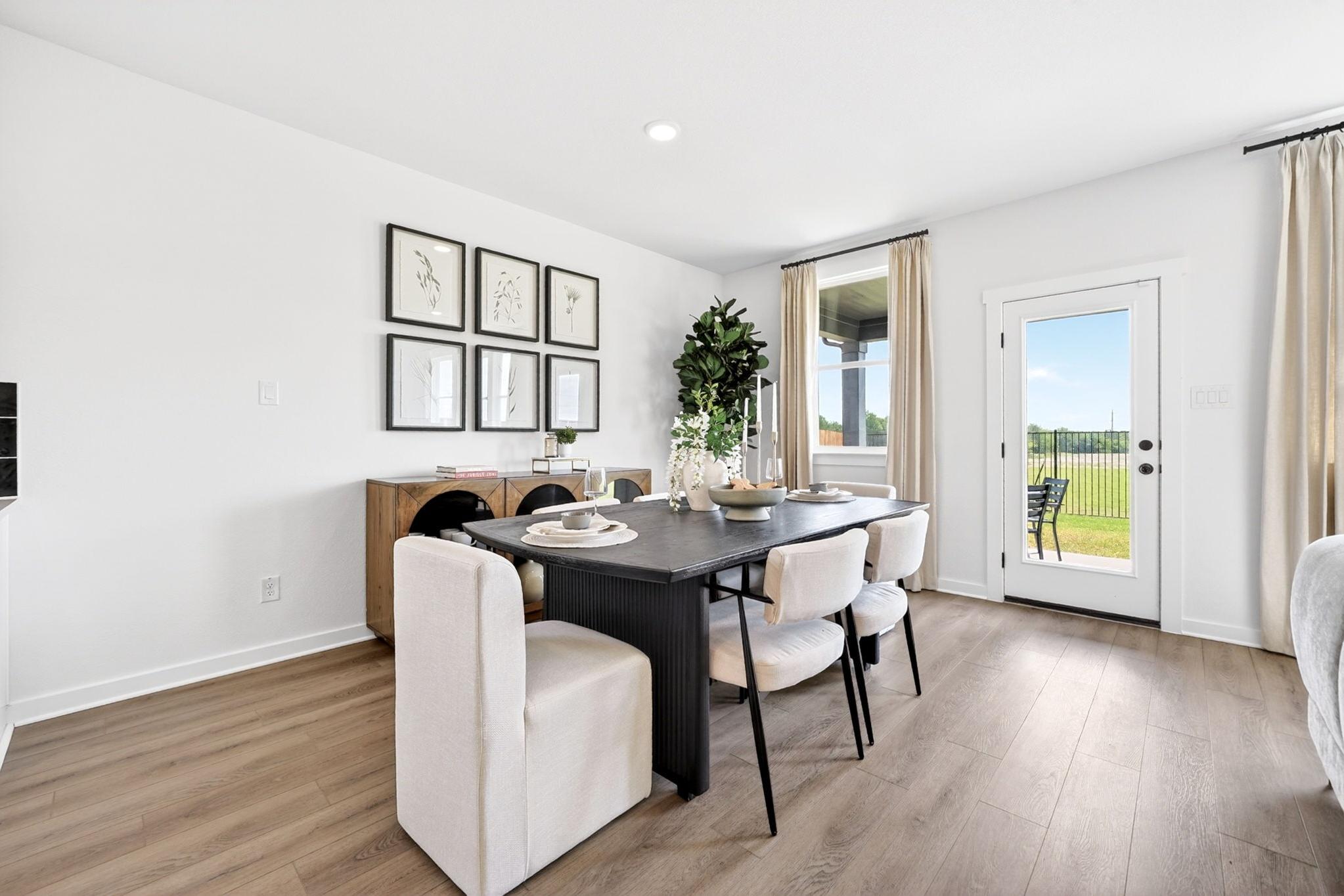 Modern dining room at Parks at Foster Crossing in Anna, TX, featuring a black table, upholstered chairs, and wood floors.