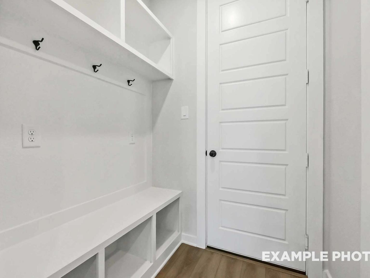 Built-in mudroom bench with storage and coat hooks in The Sequoia C floor plan by Davidson Homes in Crosby, Texas.