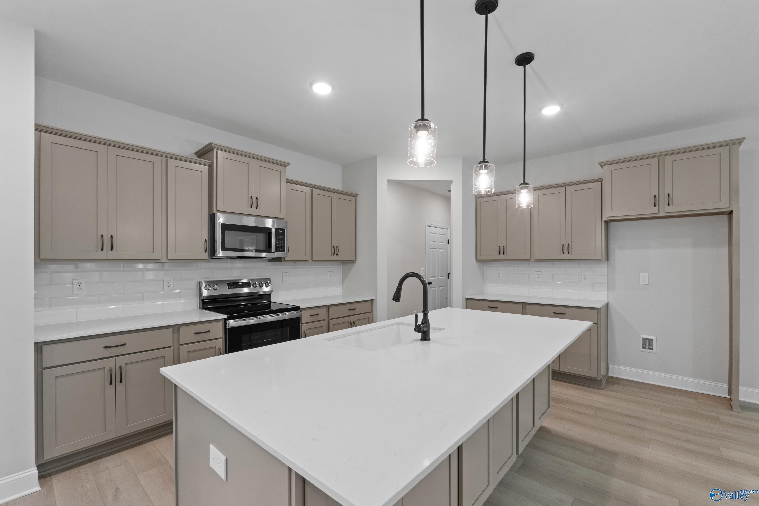 Modern kitchen with white quartz island, stainless appliances, subway tile backsplash in Davidson Homes The Kirkland with Bonus, Harvest AL