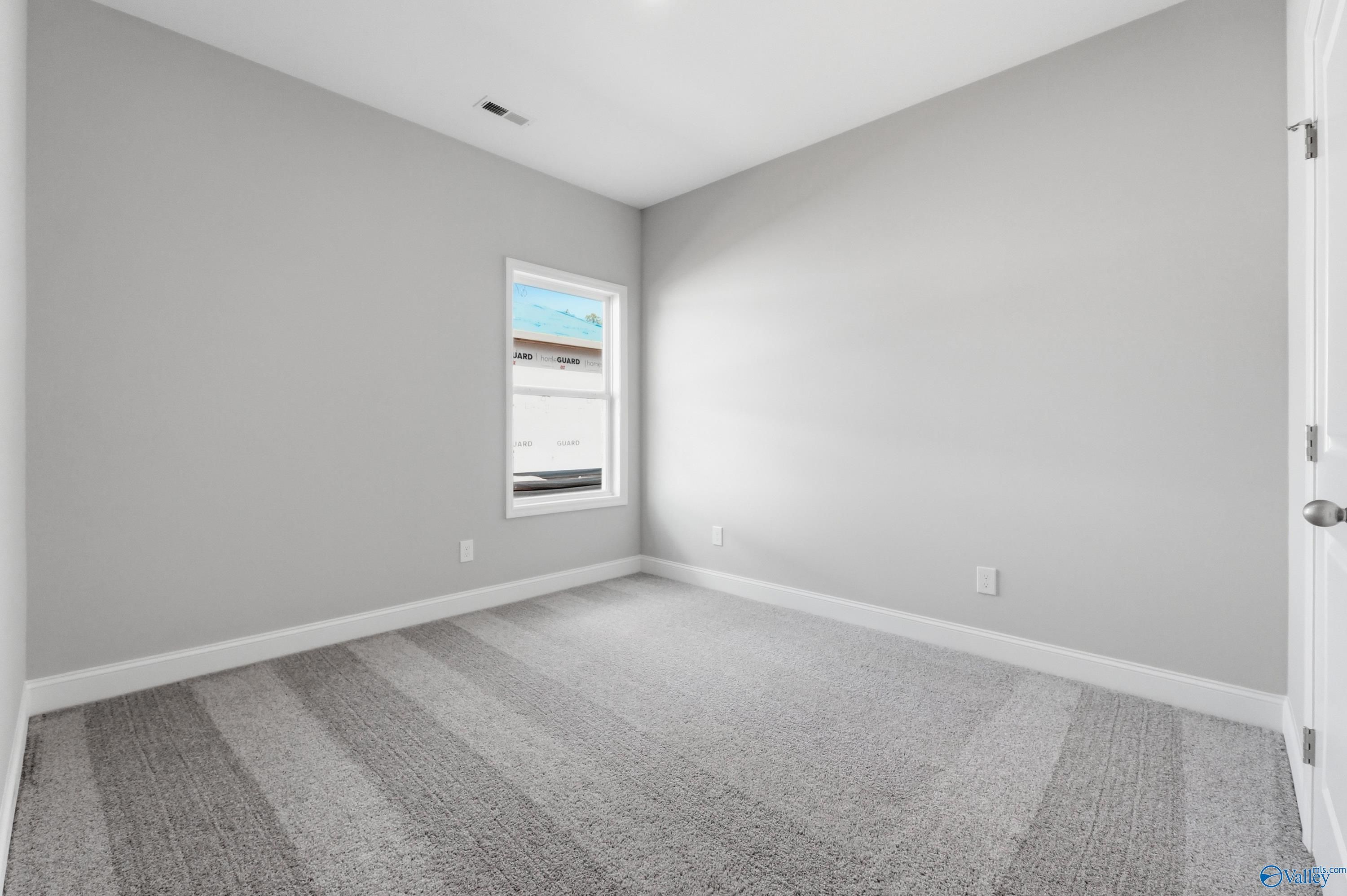 Empty secondary bedroom featuring light gray walls, plush carpet, and window with blinds in The Asheville floor plan, Huntsville AL