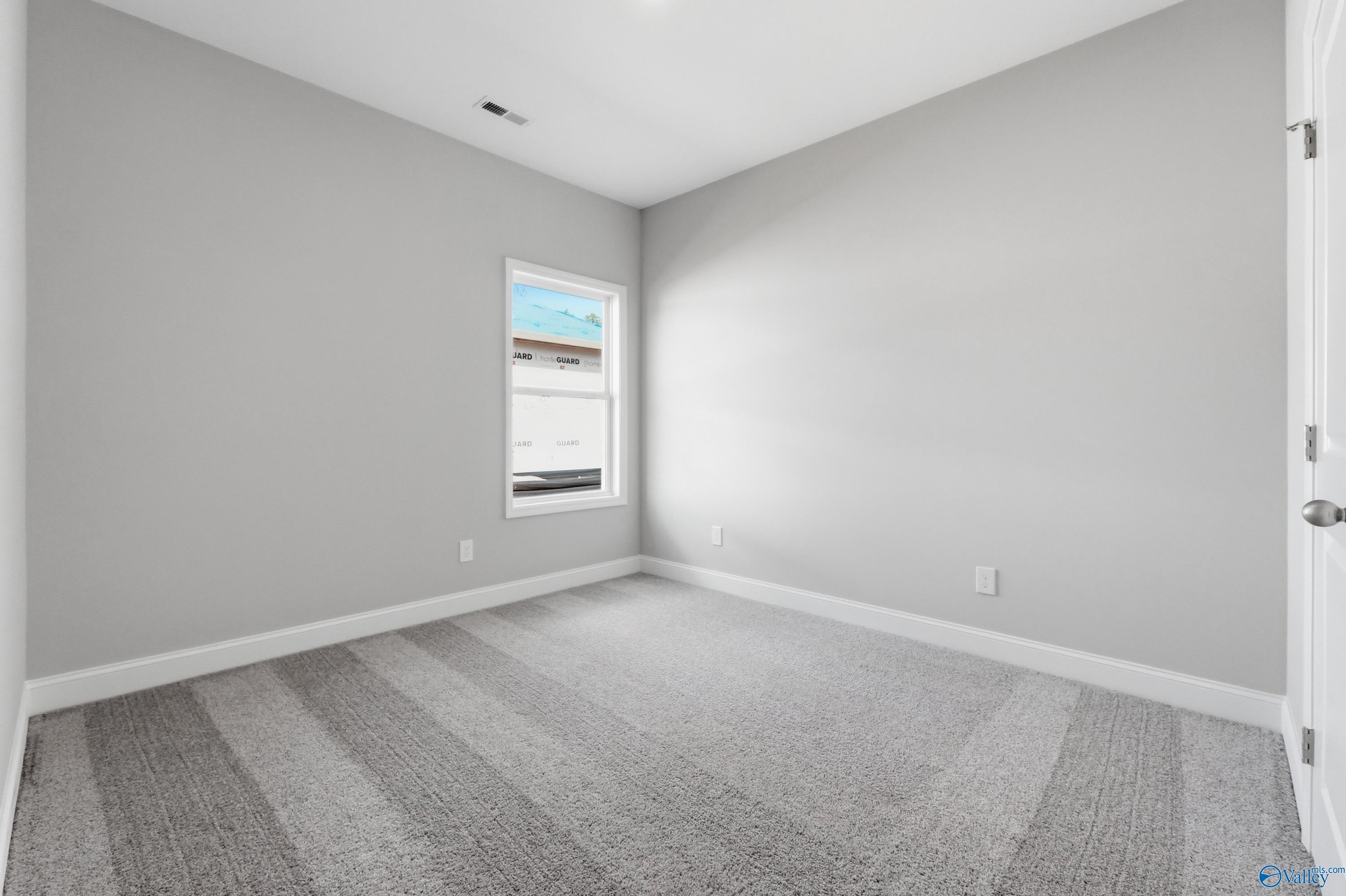 Empty secondary bedroom featuring light gray walls, plush carpet, and window with blinds in The Asheville floor plan, Huntsville AL