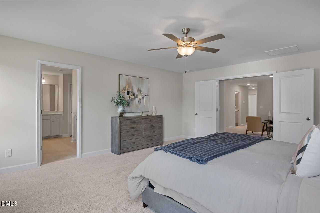 Spacious master bedroom with king bed, ceiling fan, dresser, and en-suite bath in Davidson Homes The Preston A, Lillington, NC
