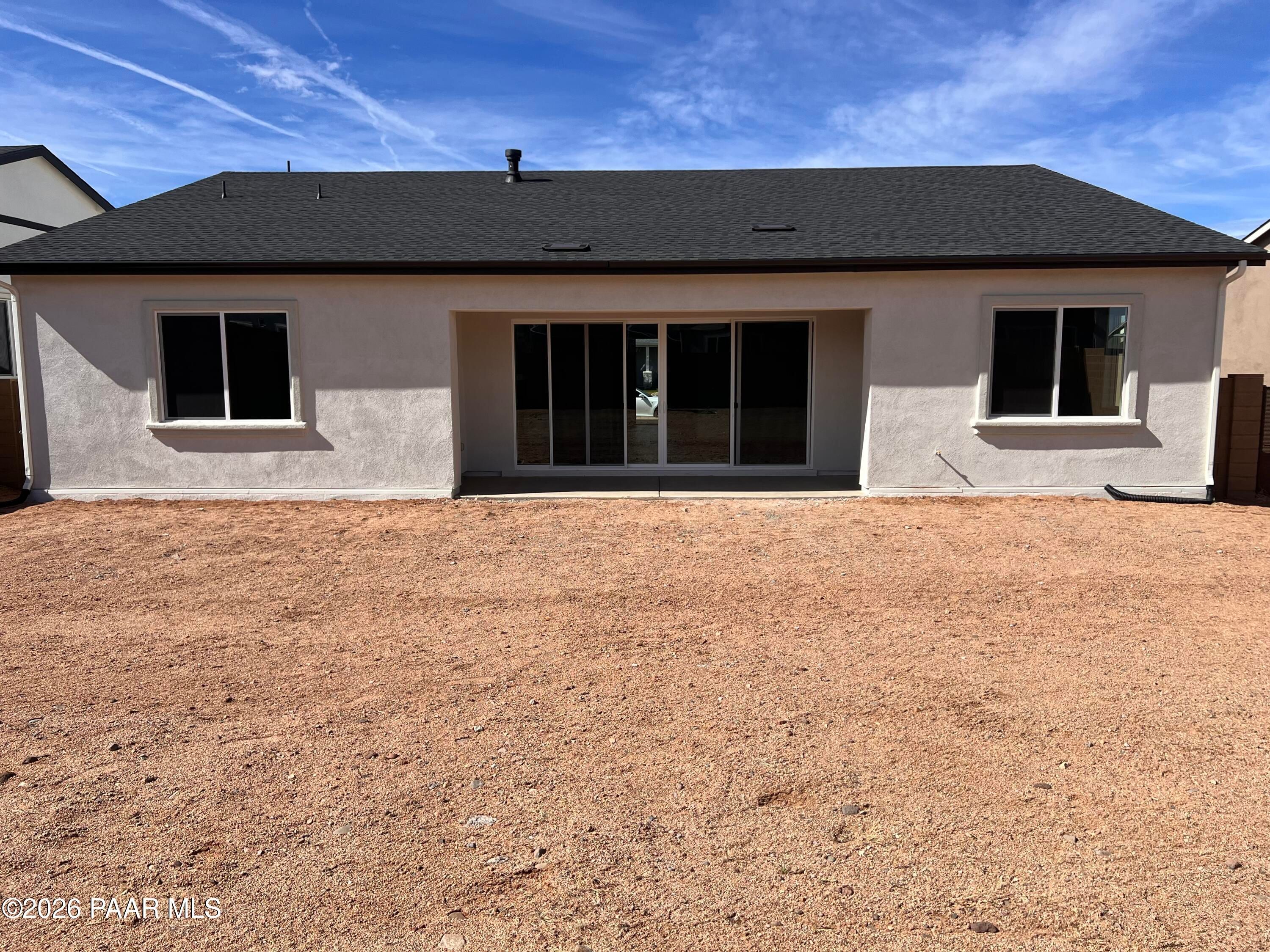 Rear view of single-story The Summit A home by Davidson Homes in Westwood, Prescott, Arizona, featuring beige stucco and sliding glass doors