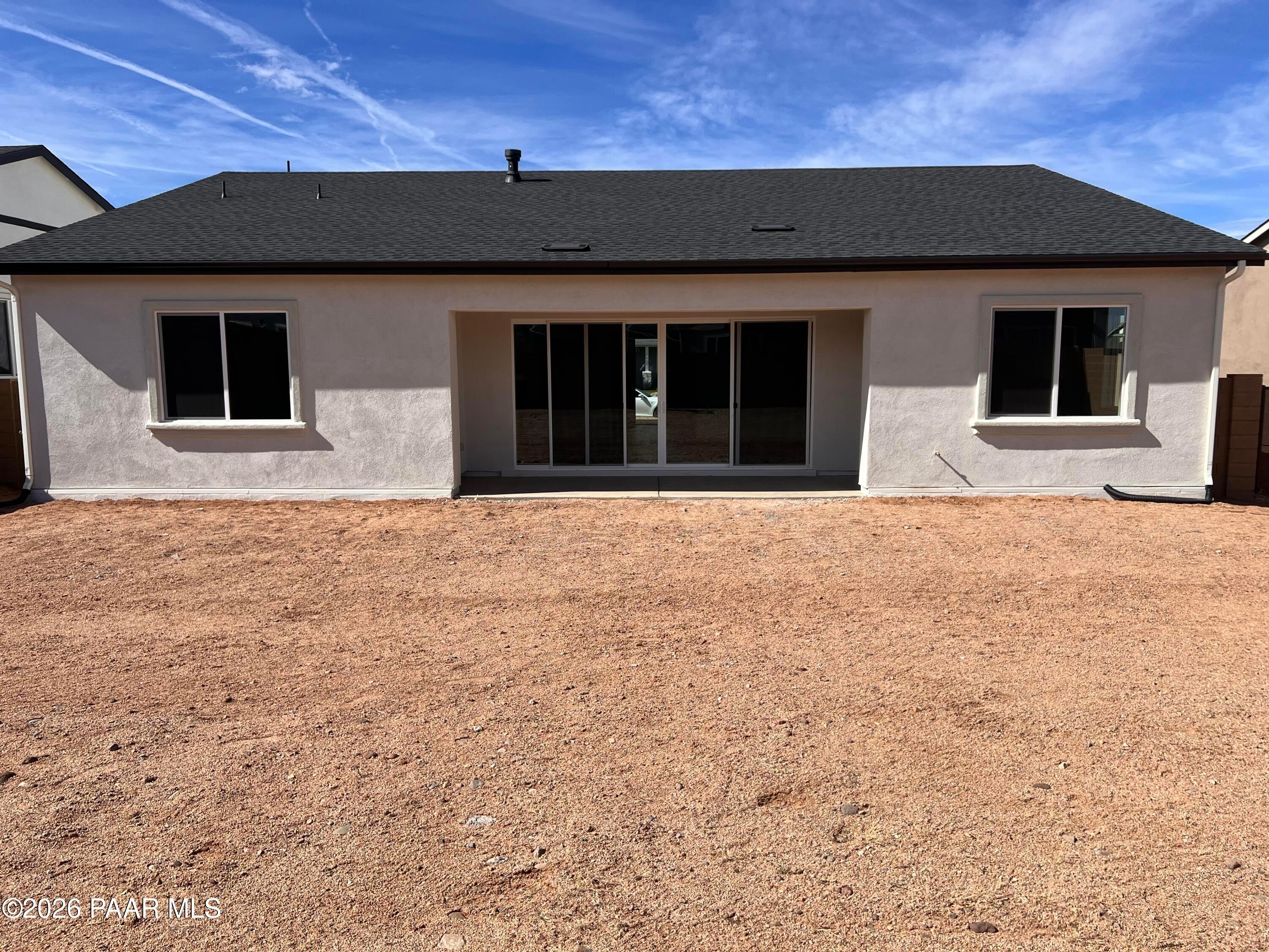 Rear view of single-story The Summit A home by Davidson Homes in Westwood, Prescott, Arizona, featuring beige stucco and sliding glass doors