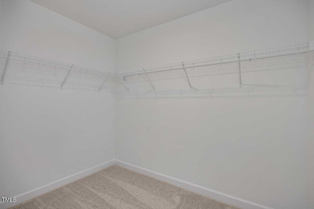 Spacious walk-in closet with white wire shelving and beige carpet in Davidson Homes The Graham, Fuquay-Varina, NC