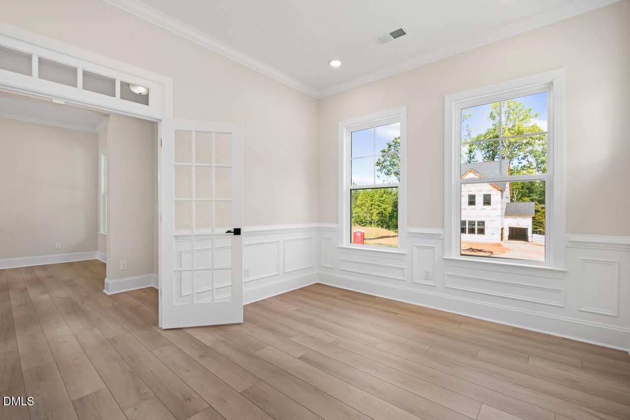 Bright flexible room with wainscoting, French door, and hardwood floors in Davidson Homes Crawford D plan, Rockport, Wake Forest NC