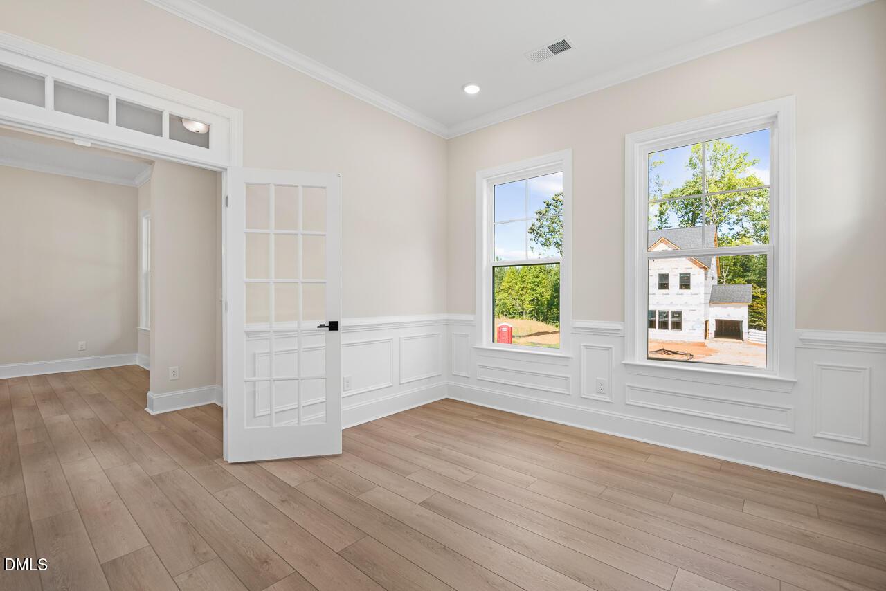 Bright flexible room with wainscoting, French door, and hardwood floors in Davidson Homes Crawford D plan, Rockport, Wake Forest NC