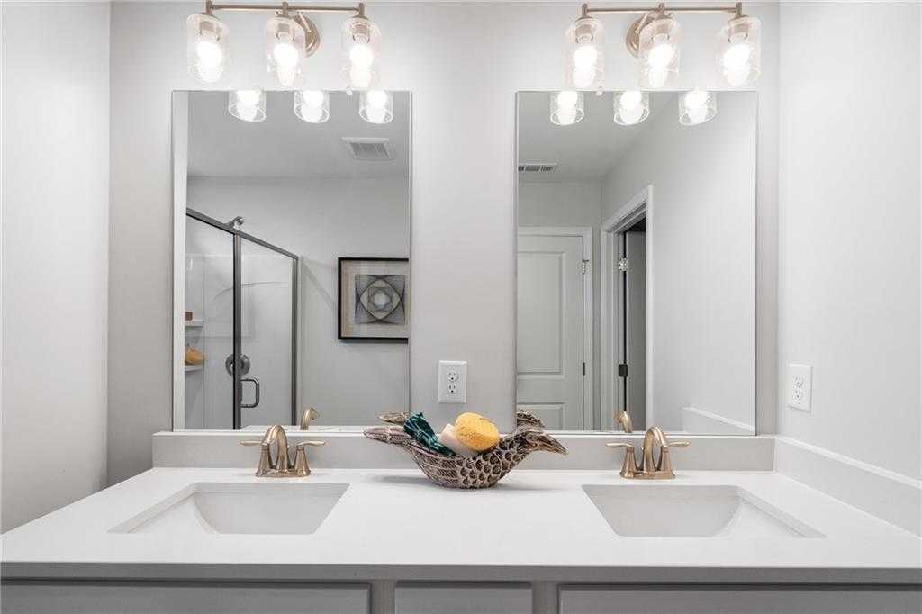 Modern double vanity with quartz countertop, dual mirrors, and glass shower in Davidson Homes Wilmington B, Emerson, Georgia
