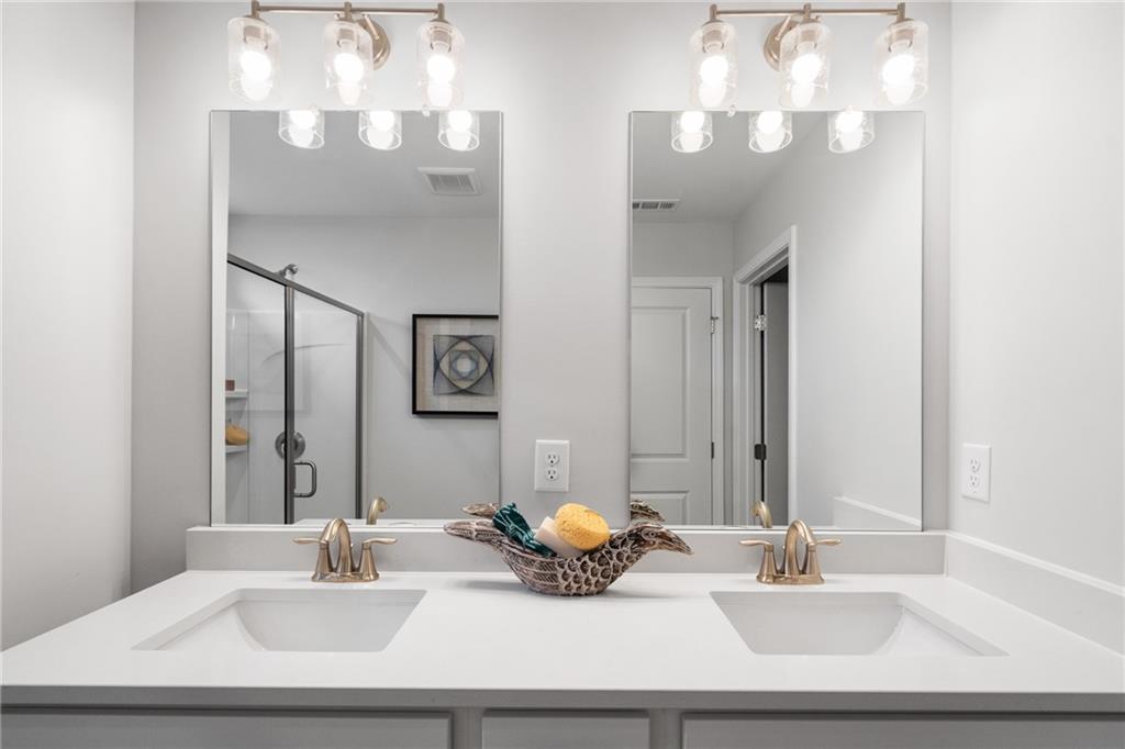 Elegant double vanity bathroom with white quartz counters, gold faucets, and fruit basket in Davidson Homes The Wilmington B, Emerson, GA