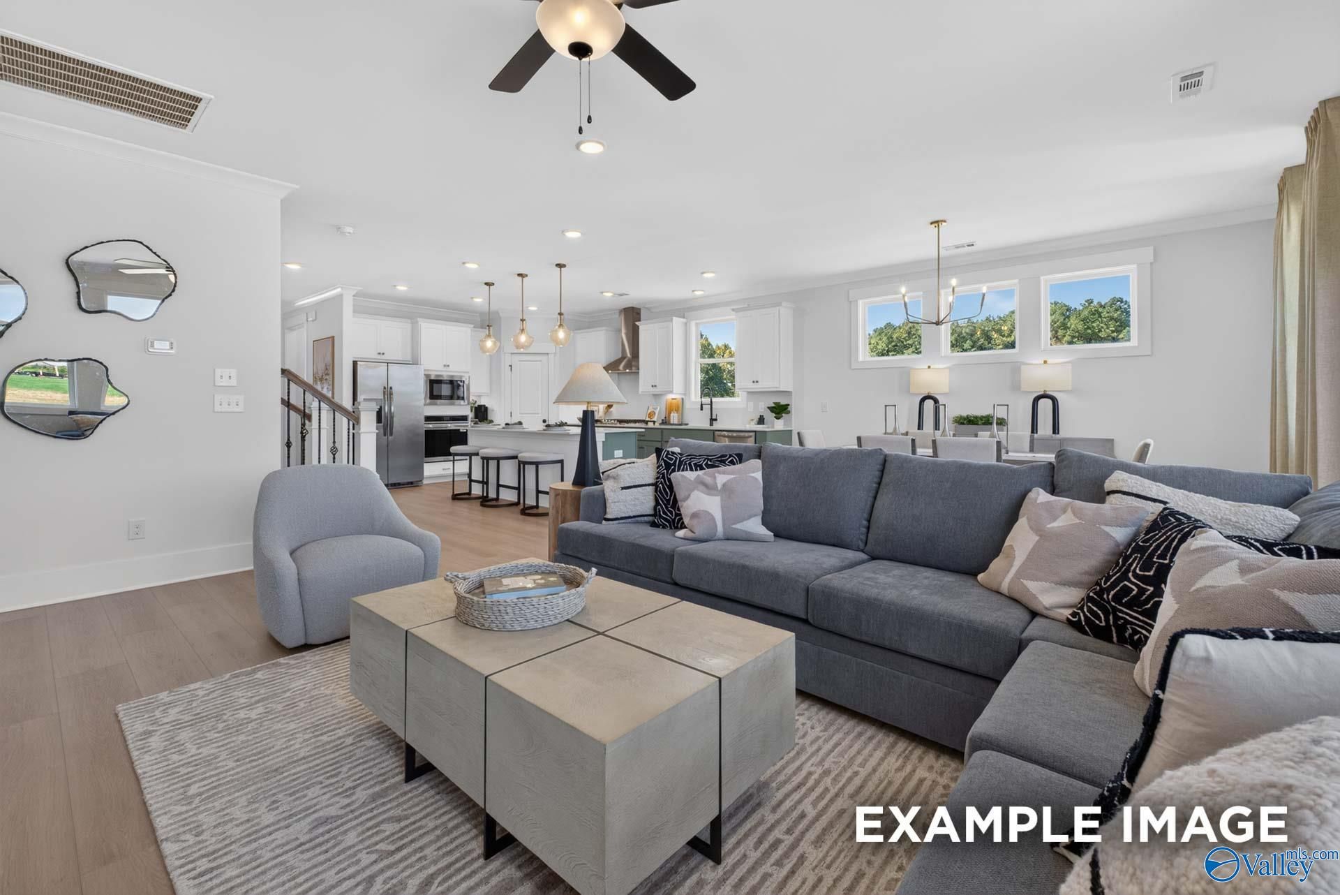 Open-concept living room and kitchen with gray sectional, white cabinetry, and stainless appliances in Davidson Homes Ashport K, Hazel Green
