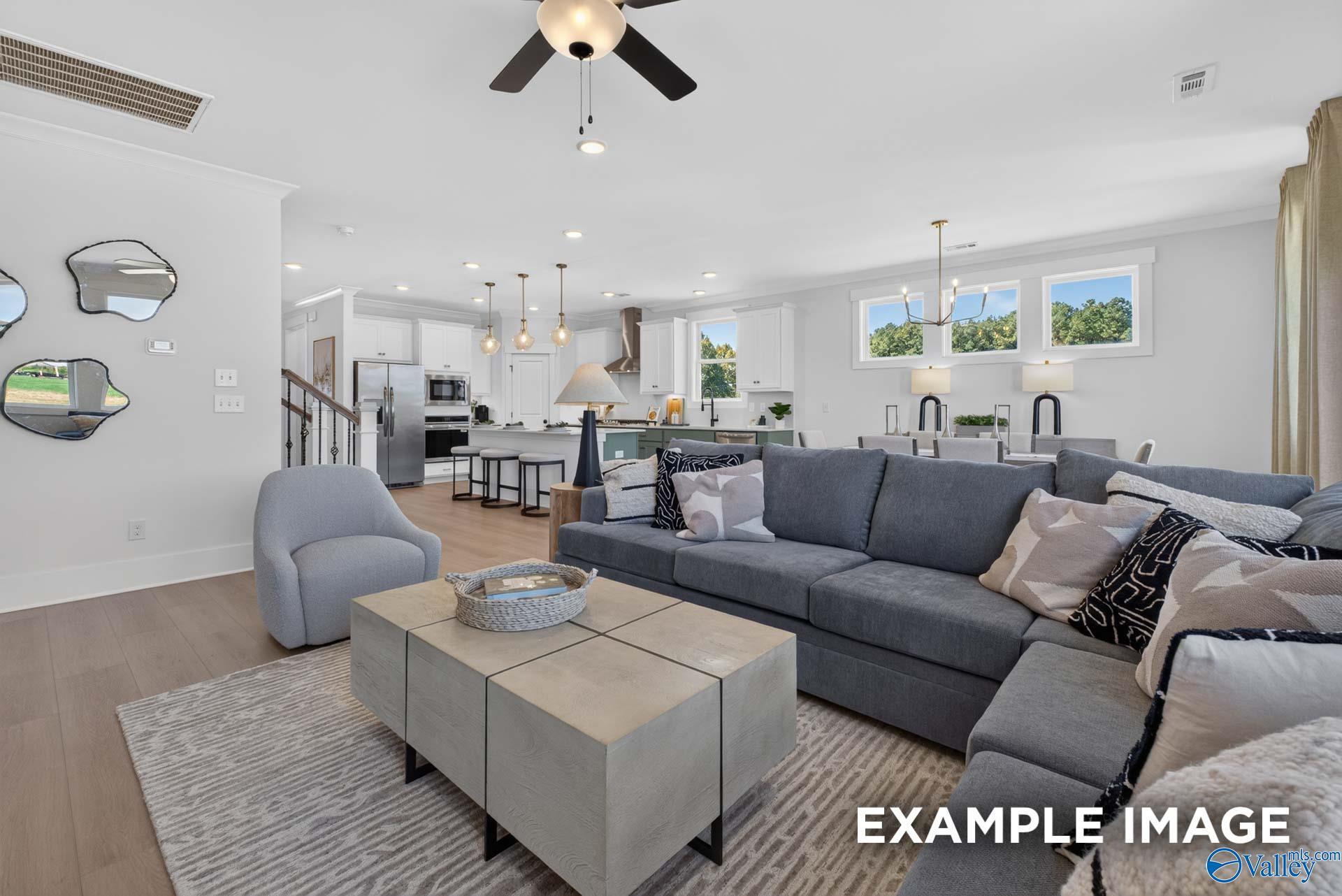 Open-concept living room and kitchen with gray sectional, white cabinetry, and stainless appliances in Davidson Homes Ashport K, Hazel Green