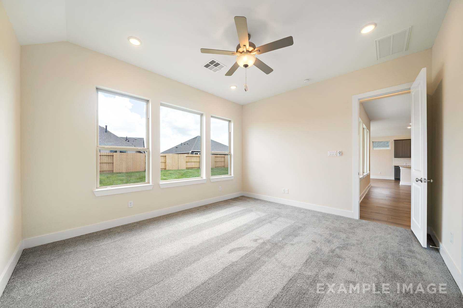 Spacious master bedroom in The Diana C featuring large windows, ceiling fan, beige walls, and open en-suite access